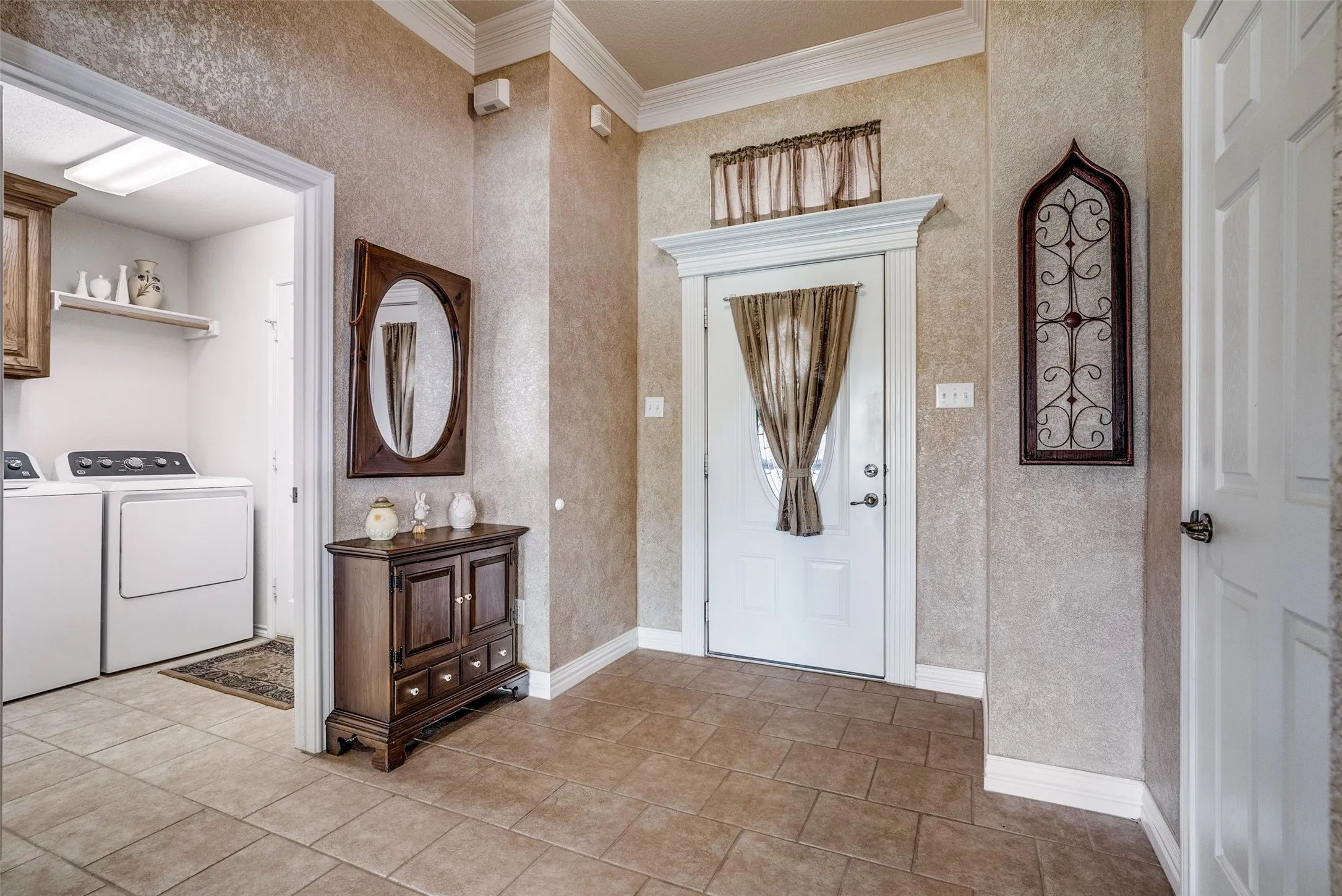 Foyer featuring separate washer and dryer and crown molding