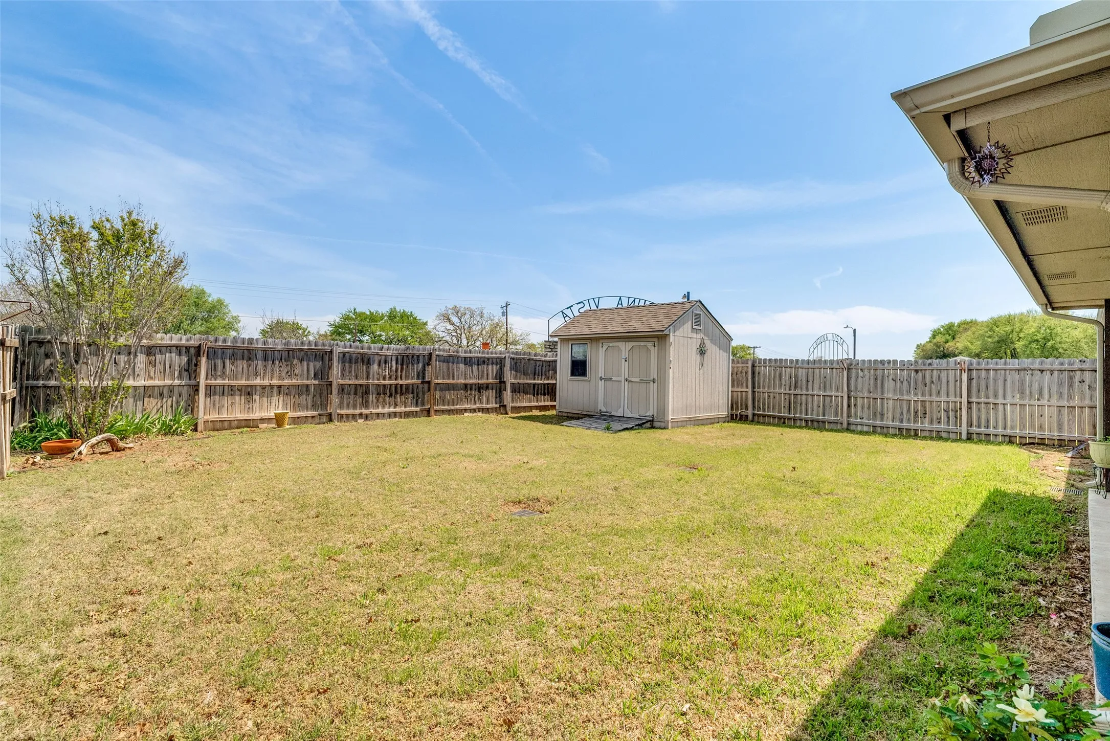 Fenced backyard featuring a storage shed
