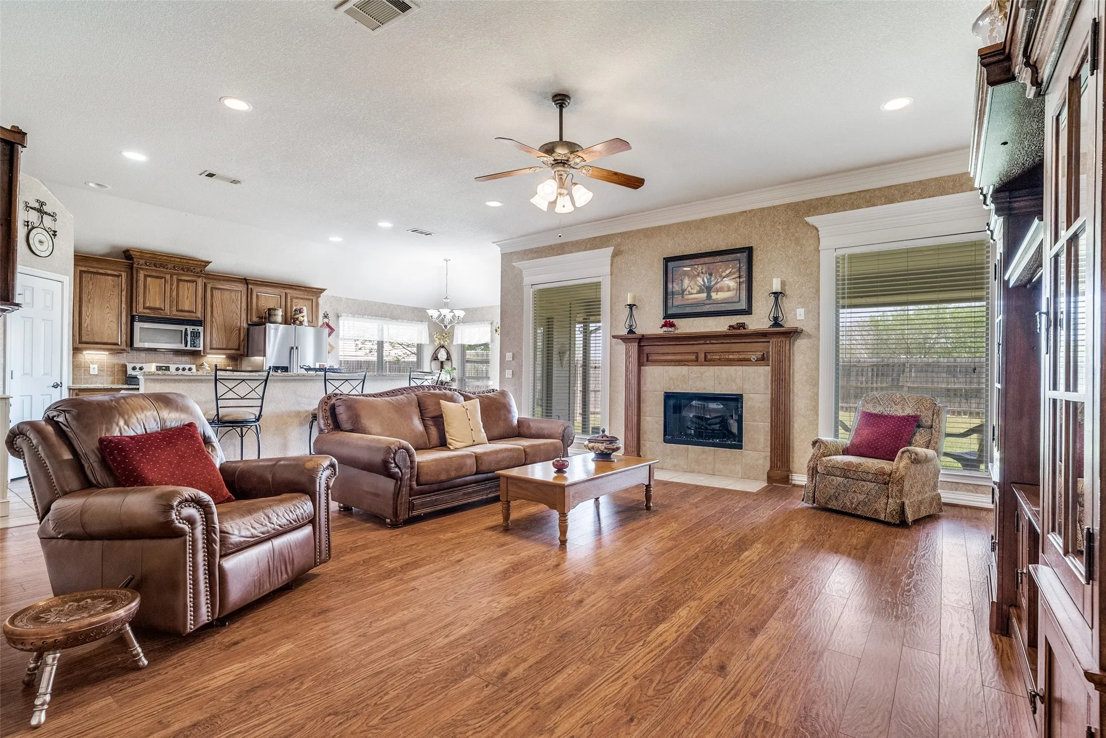 Living room with a fireplace, dark wood-type flooring, a ceiling fan, and recessed lighting