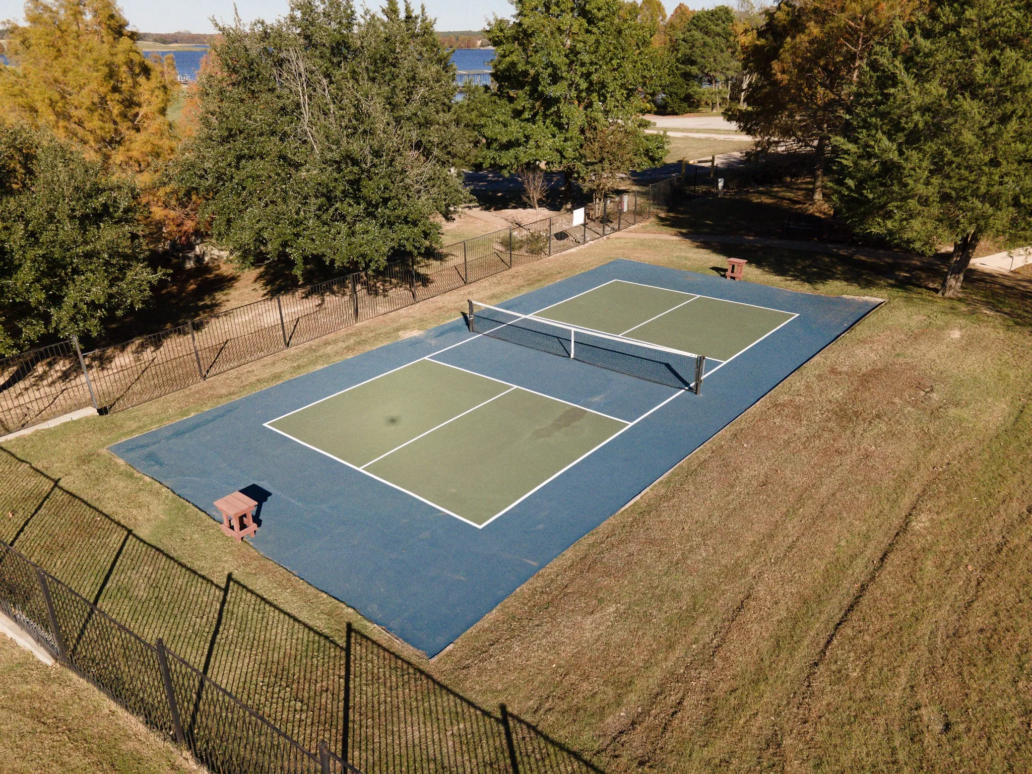 View of sport court with fence and a lawn