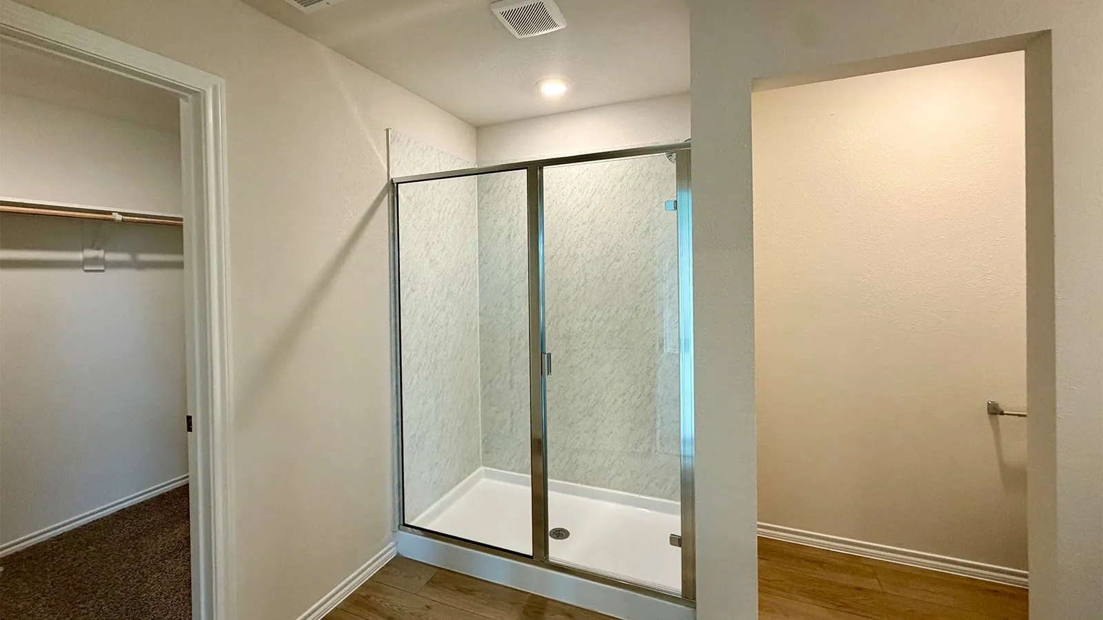 Contemporary shower enclosure with sliding glass doors, a white shower pan, and textured wall paneling
