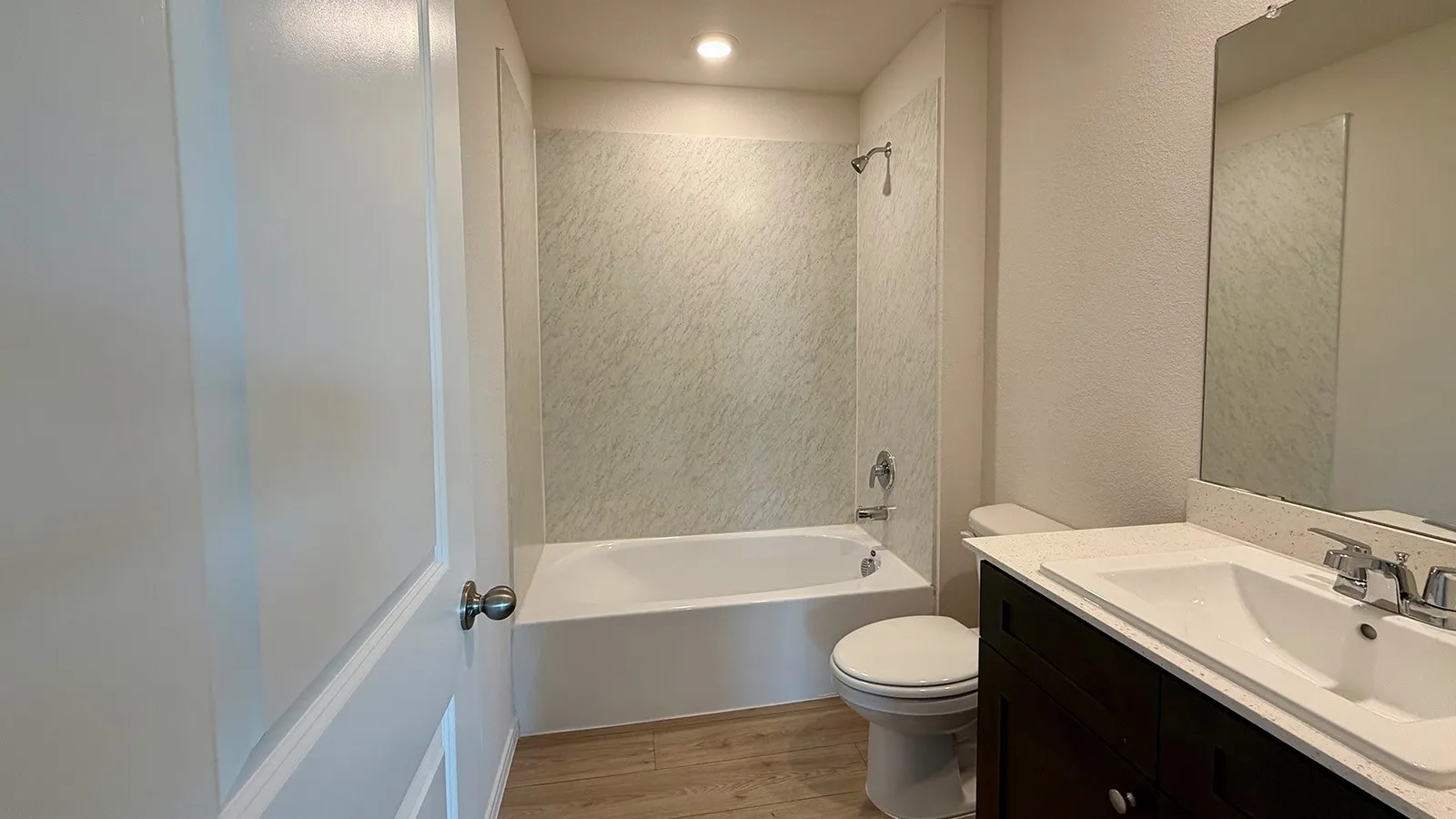 Bathroom featuring a dark wood-finish vanity with a light countertop, integrated sink, and a large wall-mounted mirror