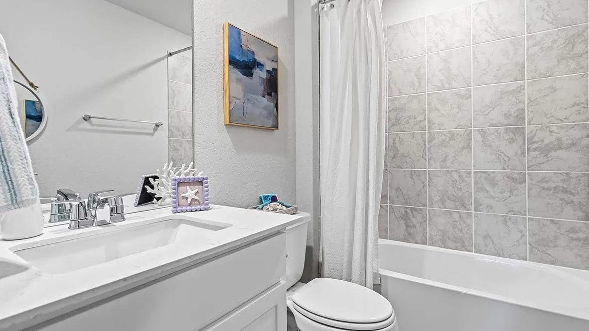 White vanity with integrated sink, chrome faucet, and expansive wall mirror