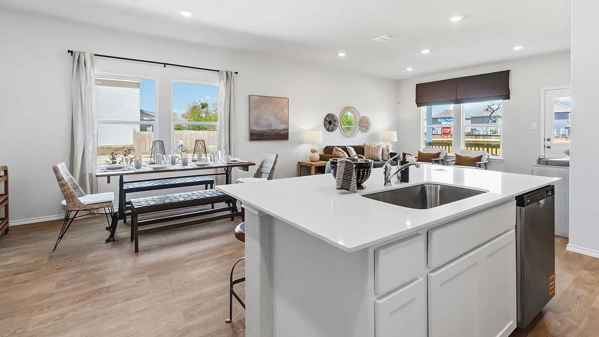 Open-concept living area featuring wood-finish flooring, recessed lighting, and a kitchen island with an undermount sink and integrated dishwasher
