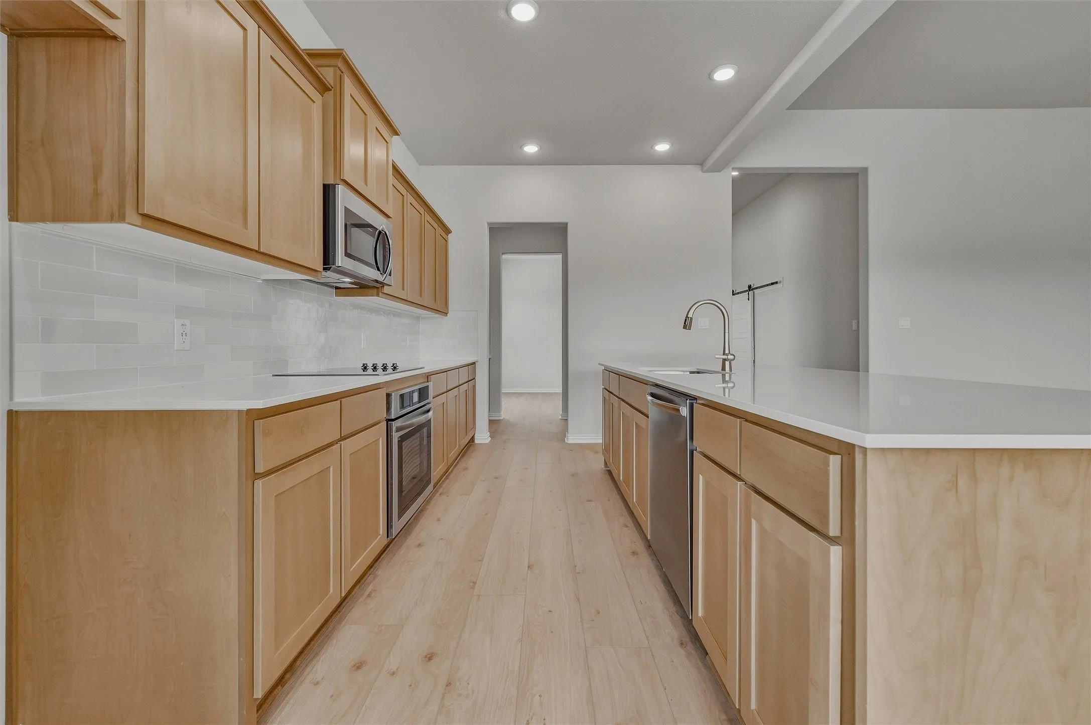 Kitchen featuring wood-finish cabinetry, stainless steel appliances, light countertops, subway tile backsplash, and recessed lighting