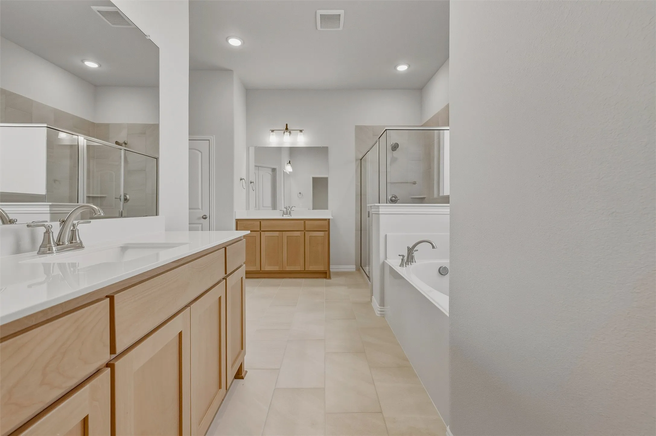 Dual vanity with light wood-finish cabinetry and white countertops