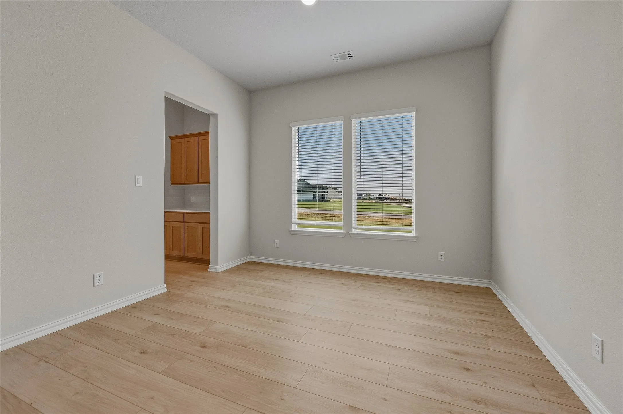 Wood-finish flooring throughout, framed by light-toned walls and crisp white trim
