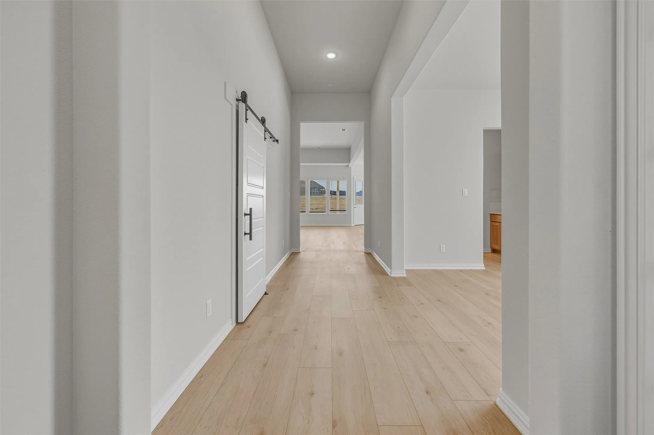 Barn door with matte black hardware, wood-finish flooring, recessed lighting, and neutral wall tones