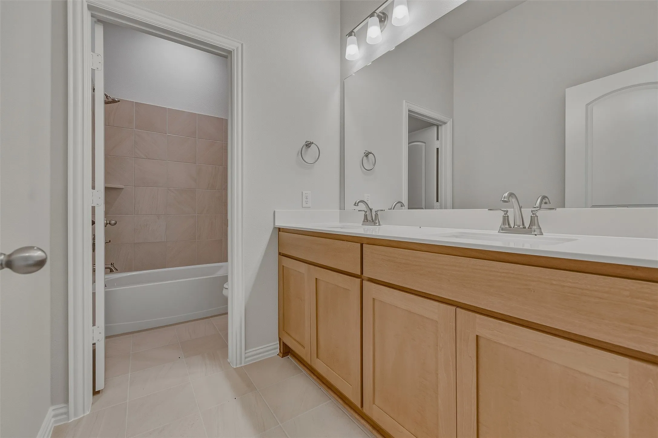 Dual vanity with undermount sinks, light-toned cabinetry, and a large wall mirror
