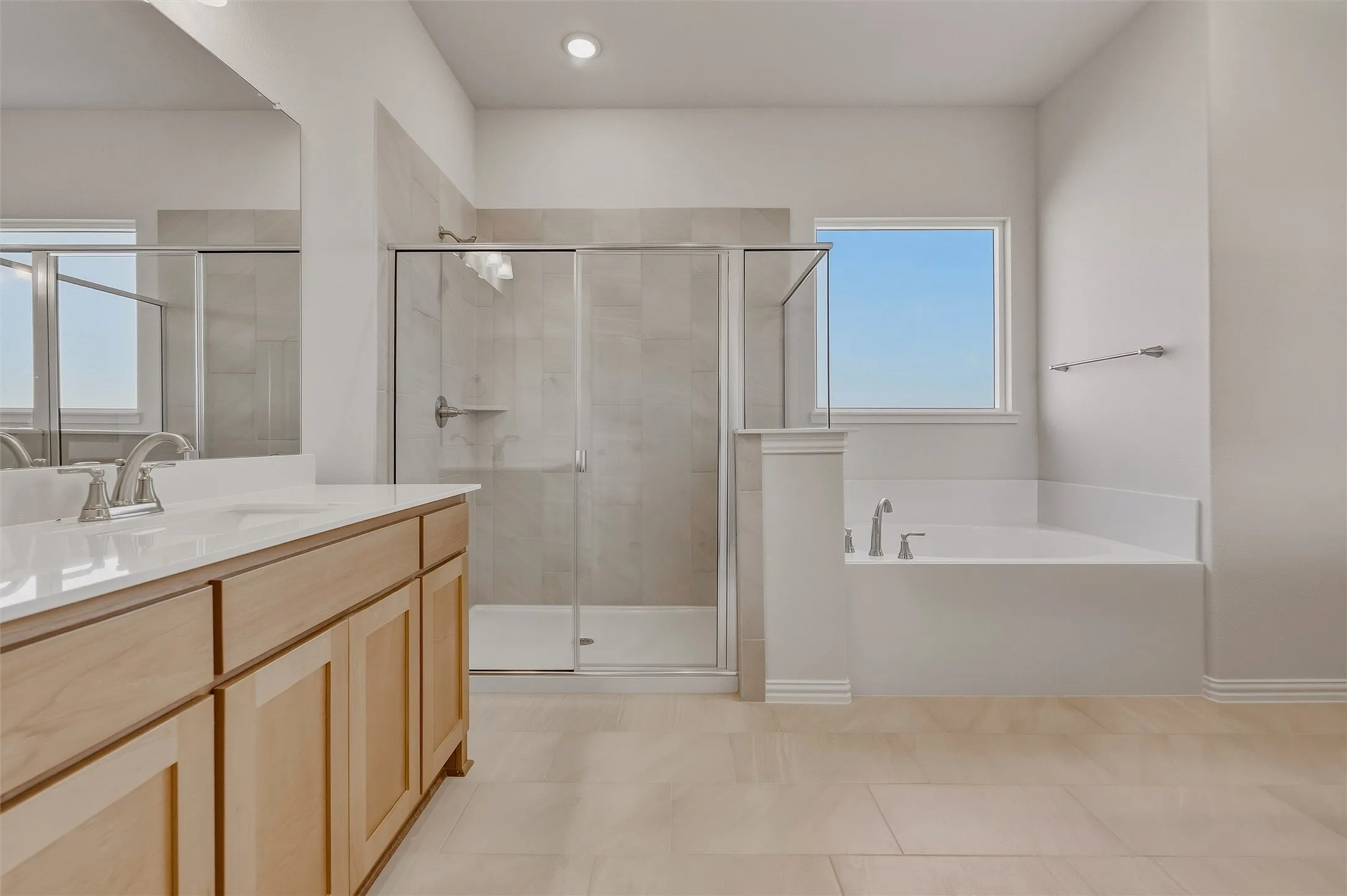 Dual vanity with light wood-finish cabinetry, white countertop, and brushed nickel fixtures