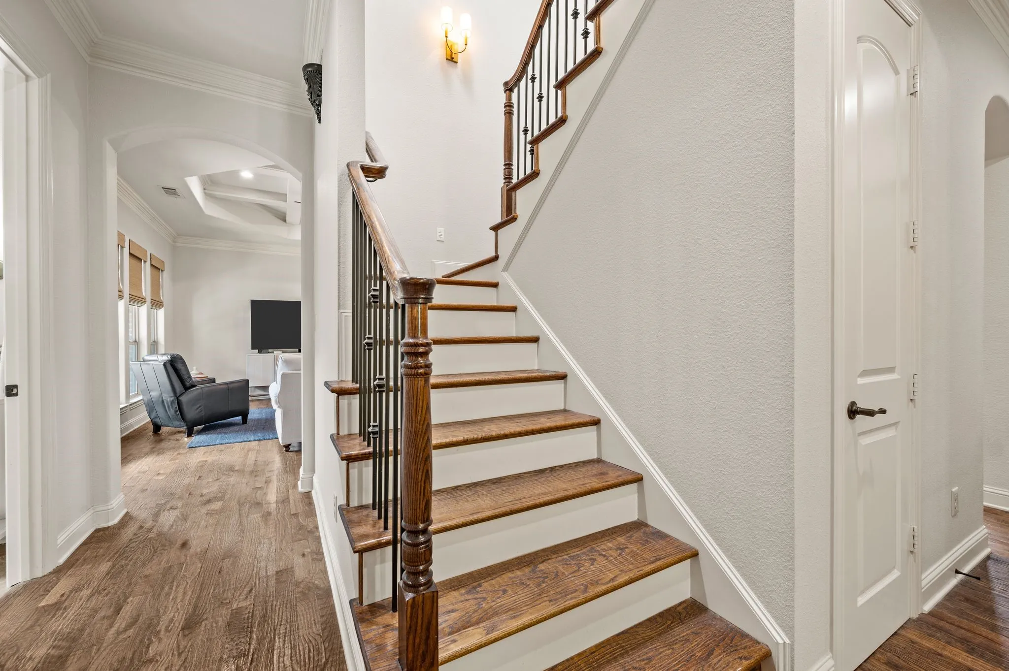Interior staircase with wood treads and wrought iron balusters leading to upper level