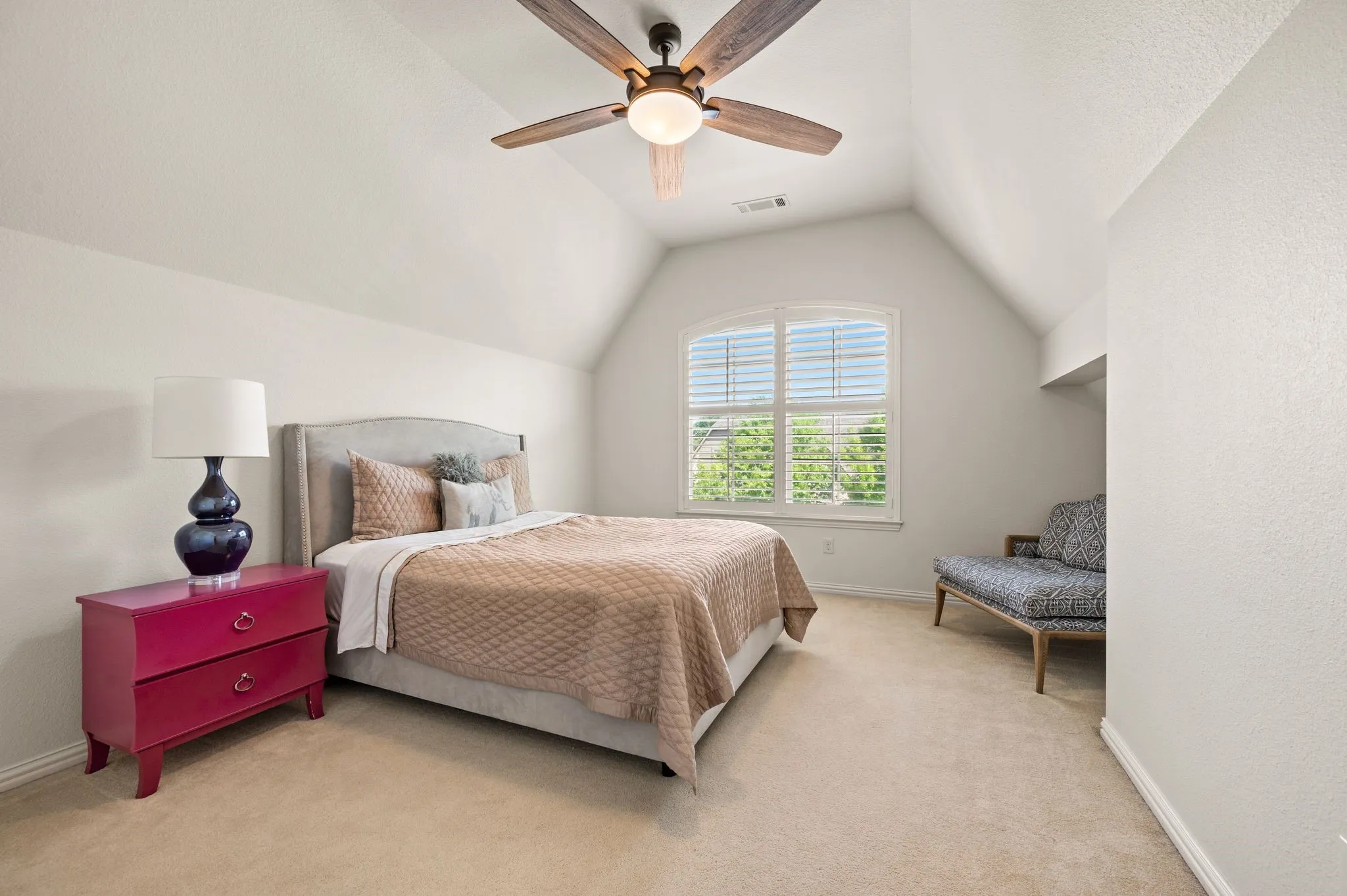 Spacious secondary bedroom with vaulted ceiling, large window, and plush carpet