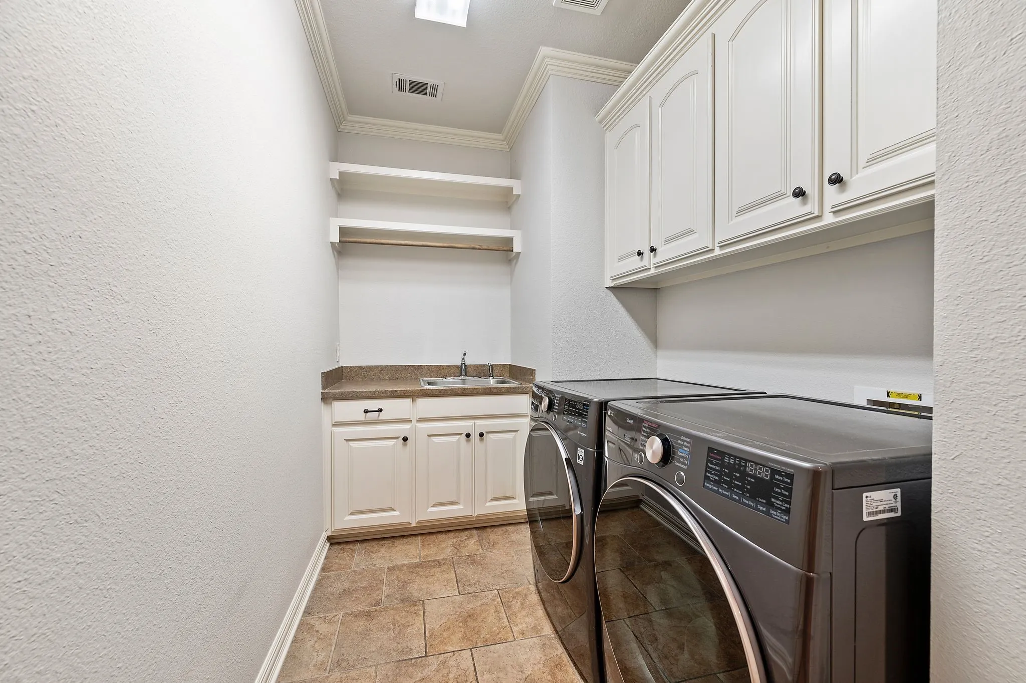 Functional laundry room with built-in cabinetry, folding space, and utility sink