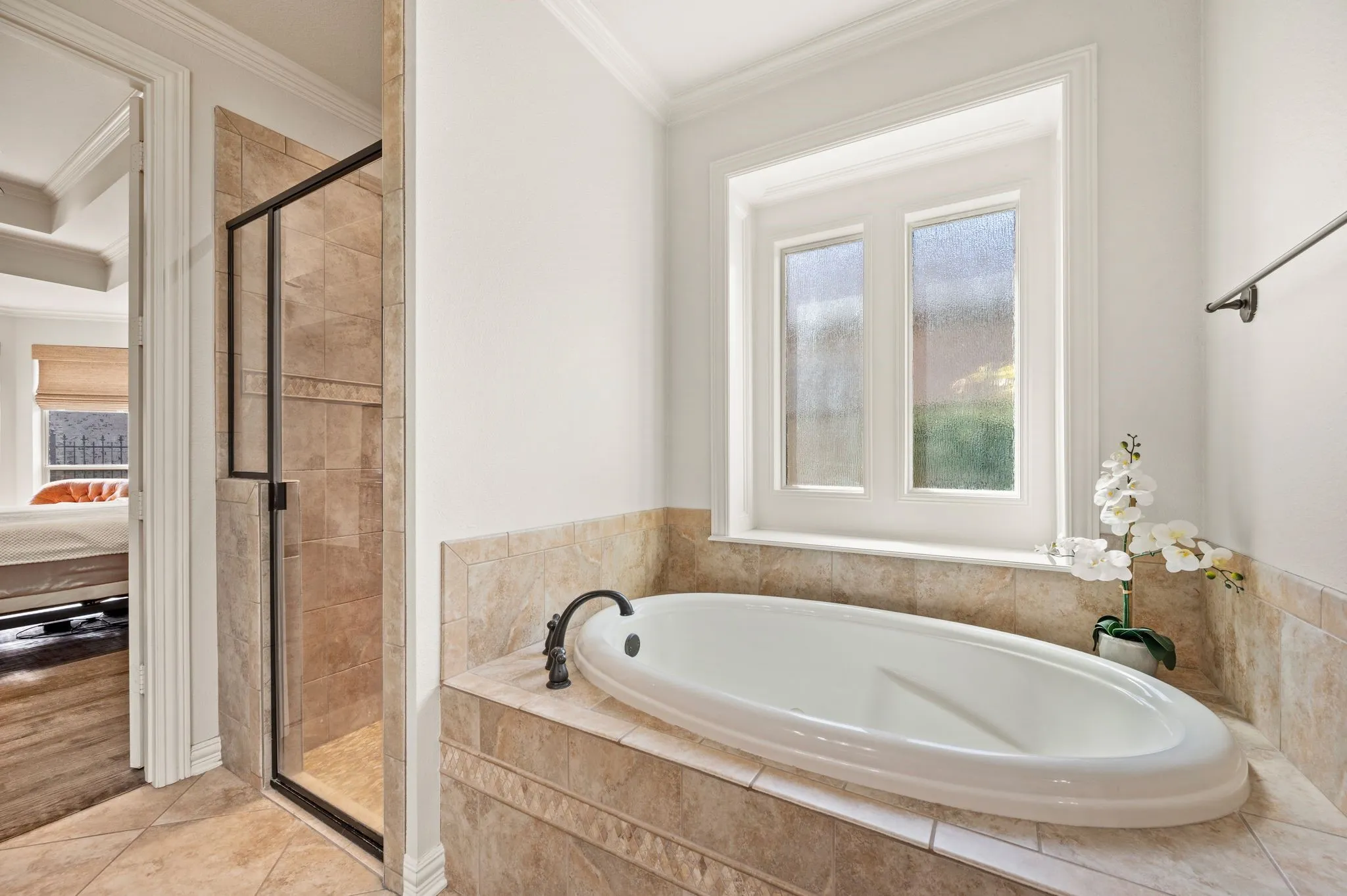Relaxing jetted tub with tile surround and frosted windows for natural light and privacy