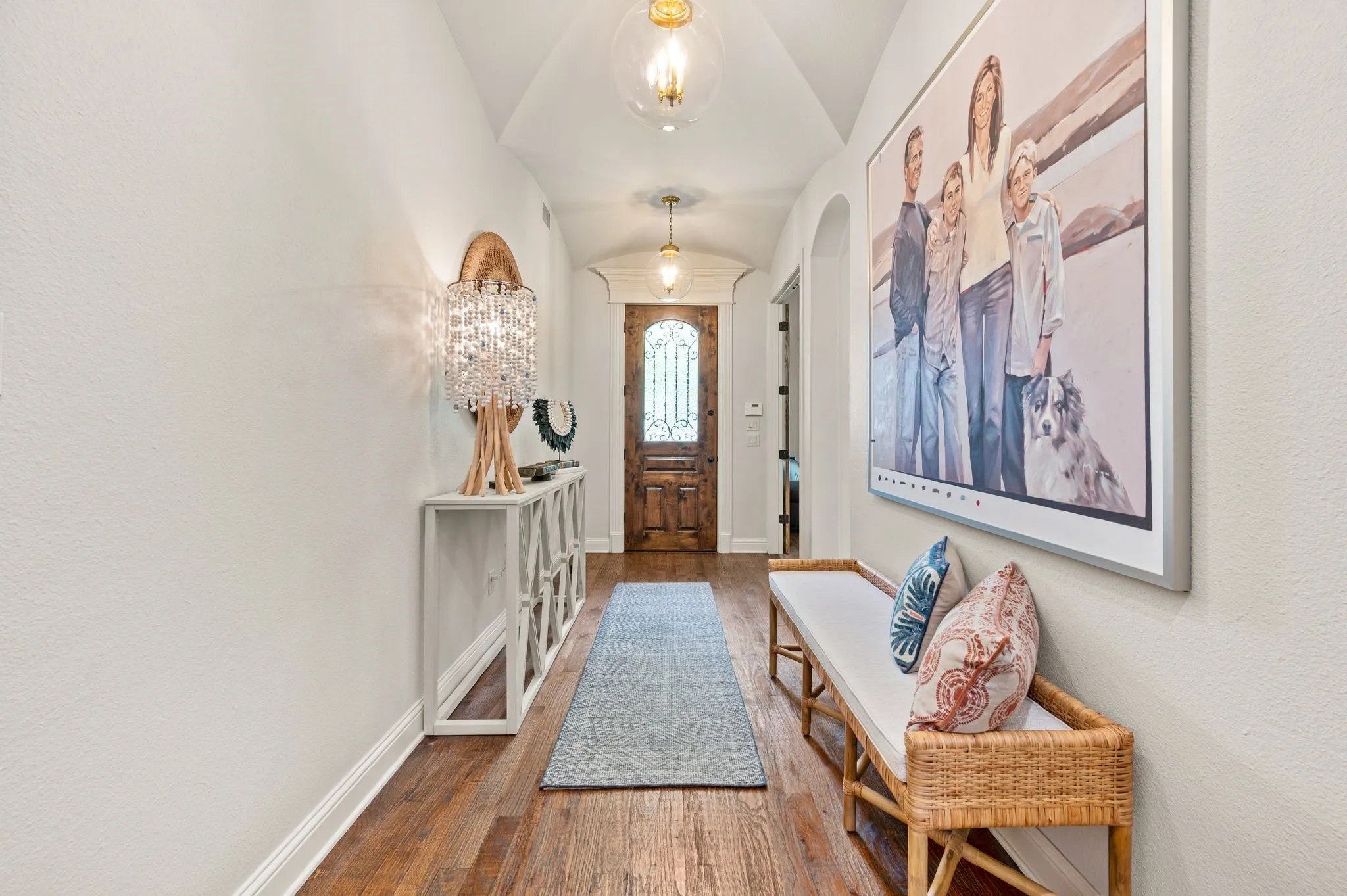 Bright and airy entry hallway with handscraped hardwood floors, high ceilings, and elegant lighting fixtures.