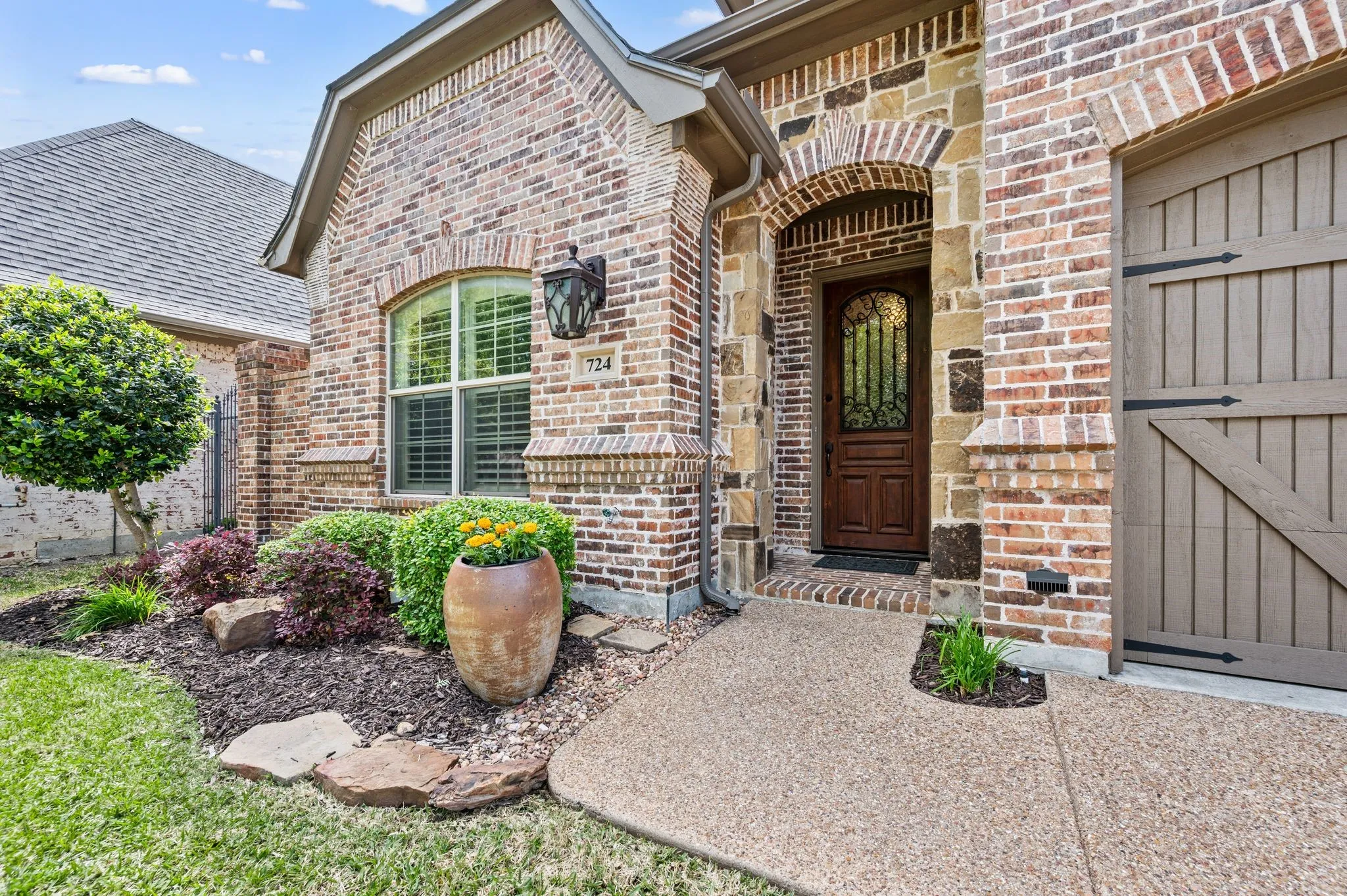 Welcoming covered entry with arched stonework, custom front door, and decorative lighting.