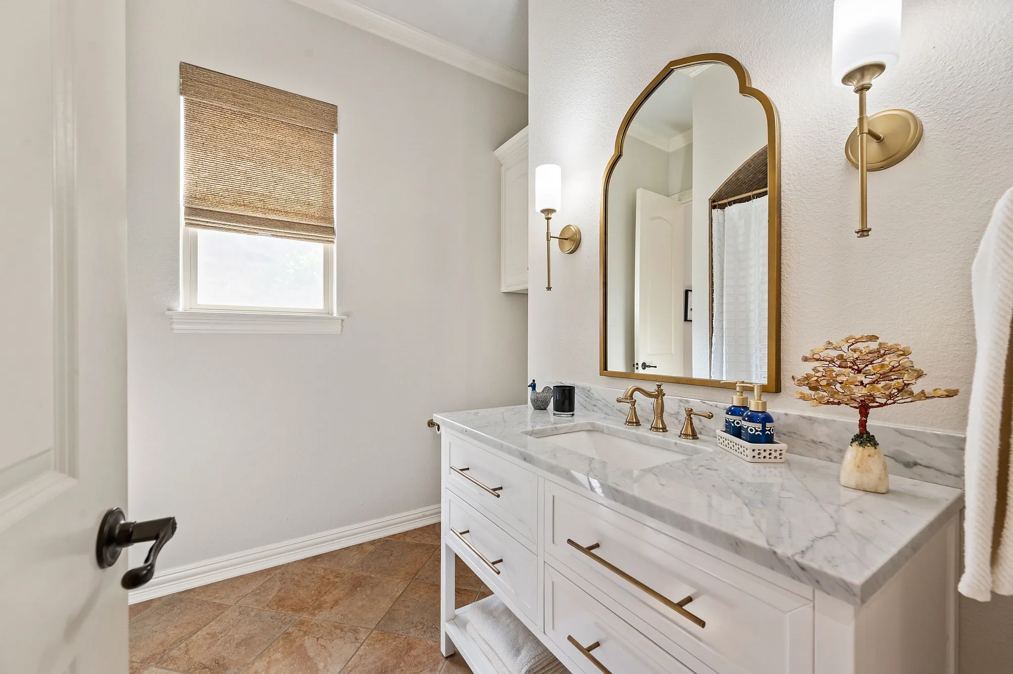Updated secondary bathroom with marble countertop, modern fixtures, and elegant gold accents