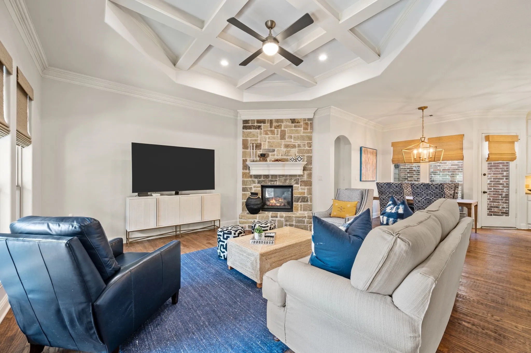 Spacious living room with coffered ceiling, recessed lighting, and stone fireplace centerpiece.