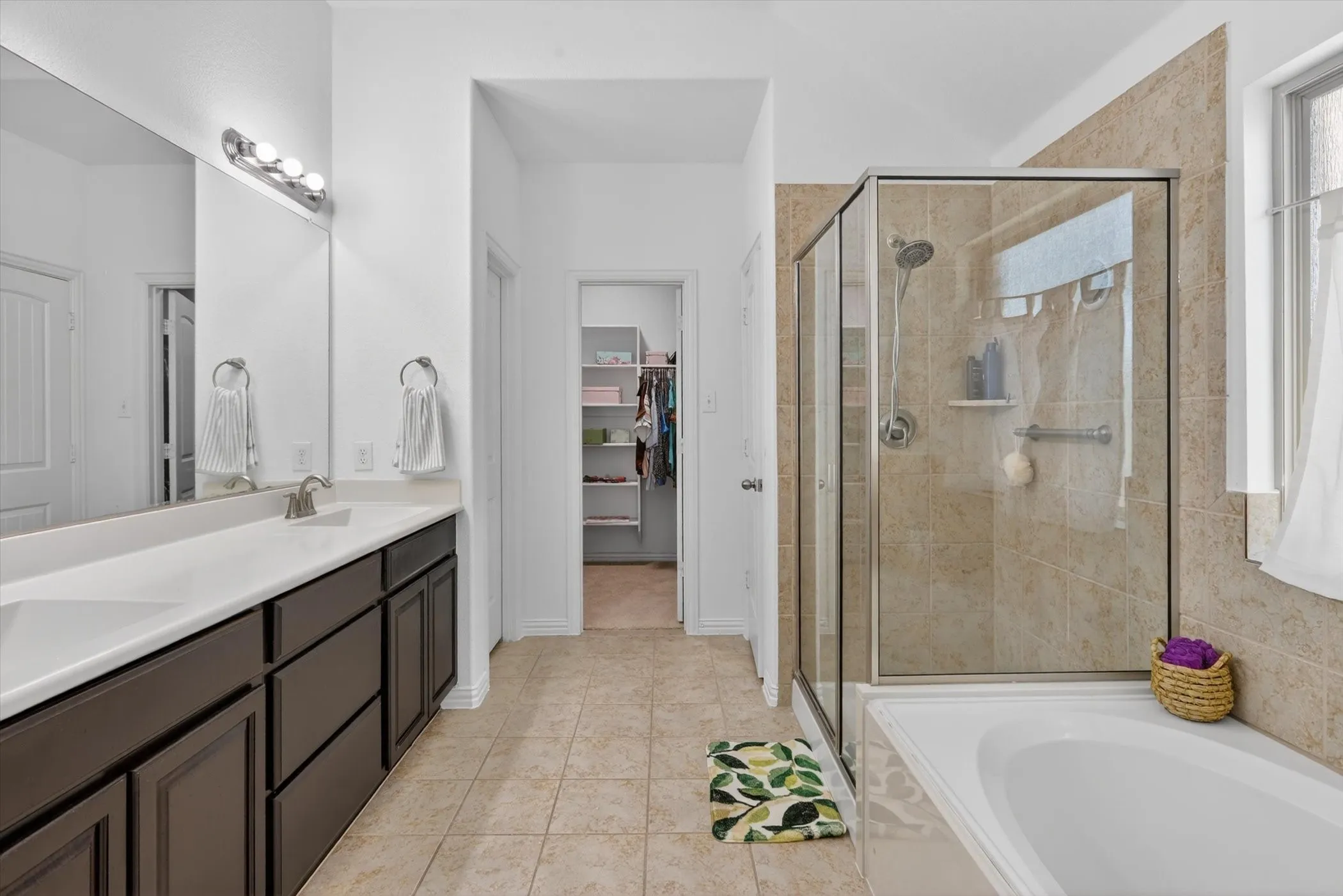 Modern bathroom featuring a double vanity with dark wood-finish cabinetry, a large mirror, and contemporary lighting