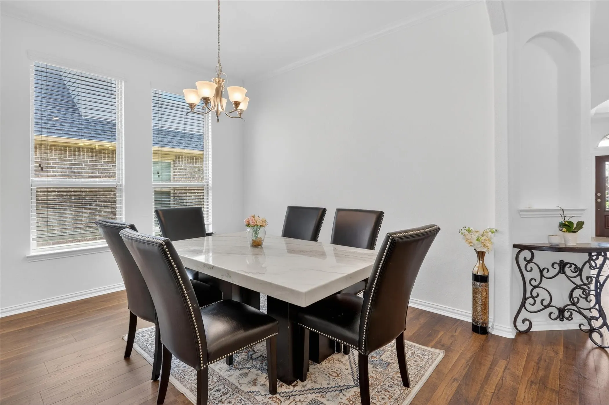 Dining area featuring wood-finish flooring, white walls, and a multi-light chandelier