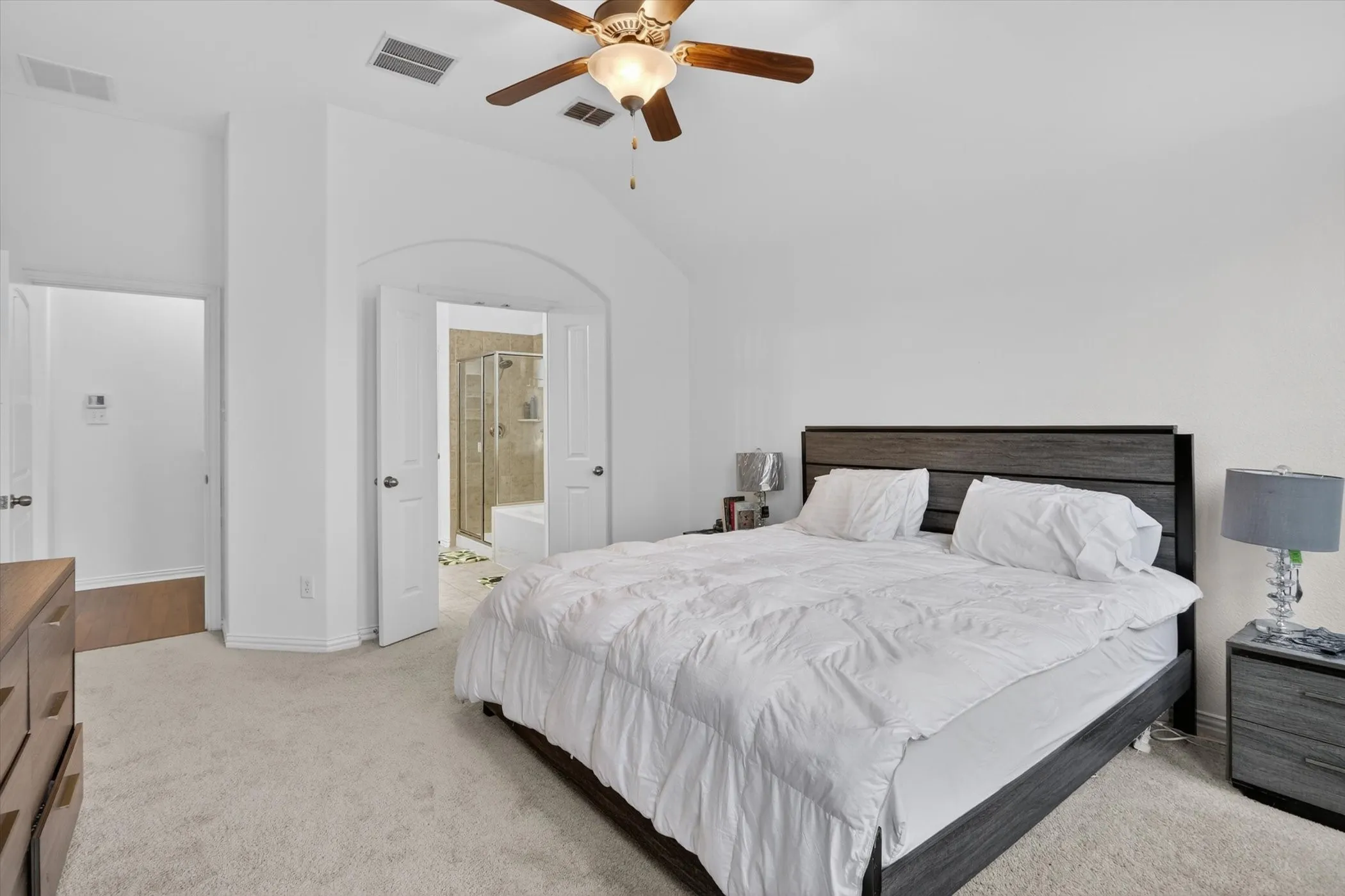 Carpeted bedroom with vaulted ceiling and a ceiling fan