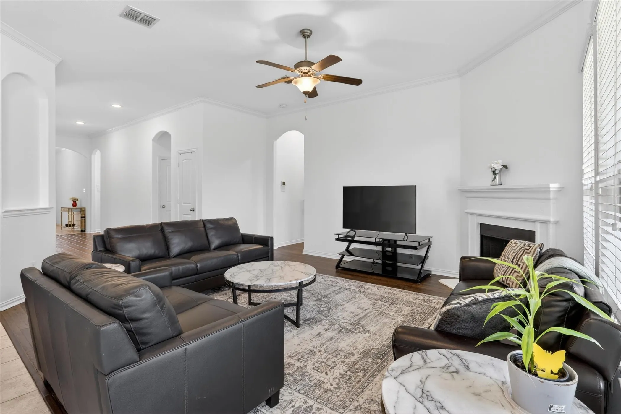 Spacious living area featuring high ceilings, wood-finish flooring, and a decorative fireplace with a mantle