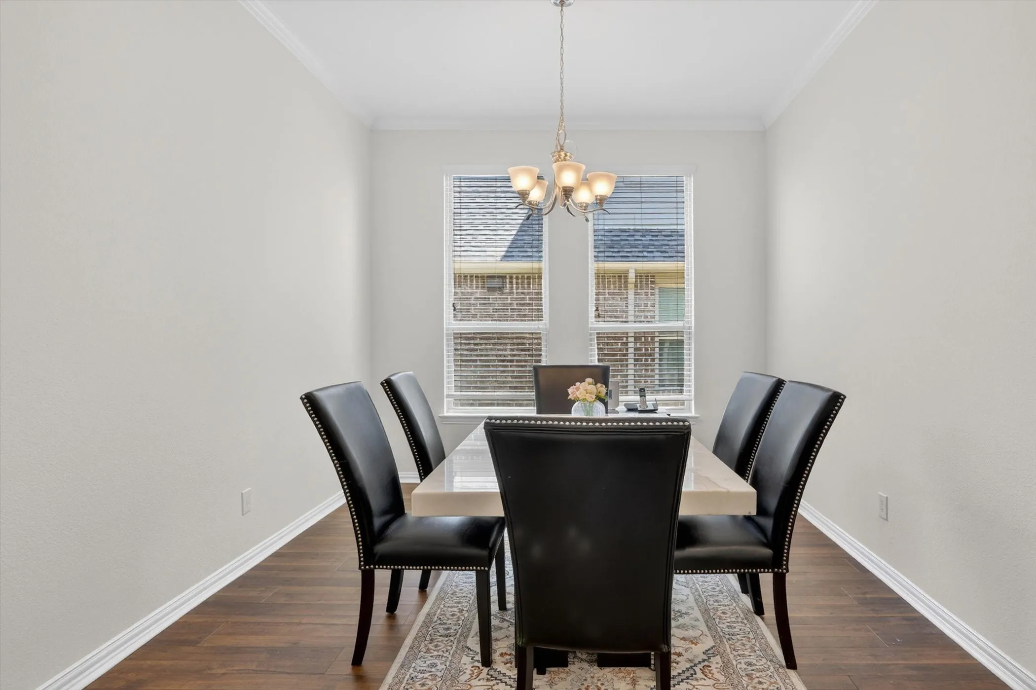 Formal dining space with wood-finish flooring, a contemporary chandelier, and crown molding