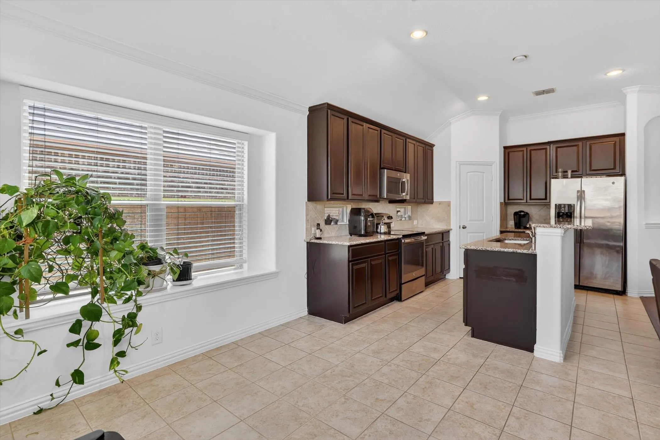 Kitchen featuring dark wood cabinetry, stainless steel appliances, and a central island with a contrasting countertop