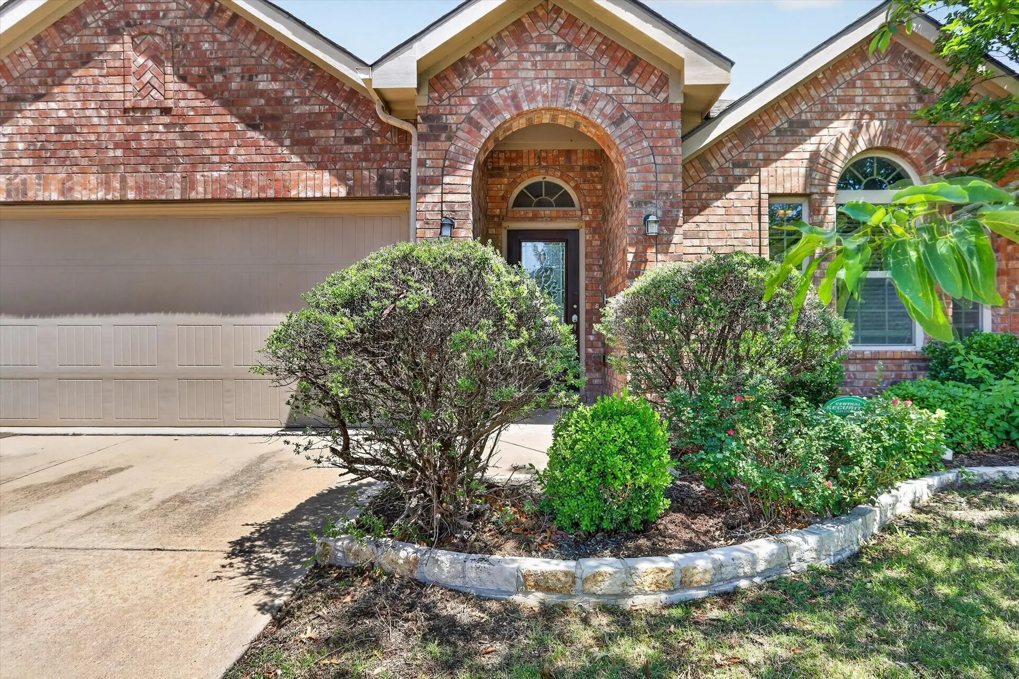 Brick facade featuring an arched entry, a garage door, and a decorative arched window