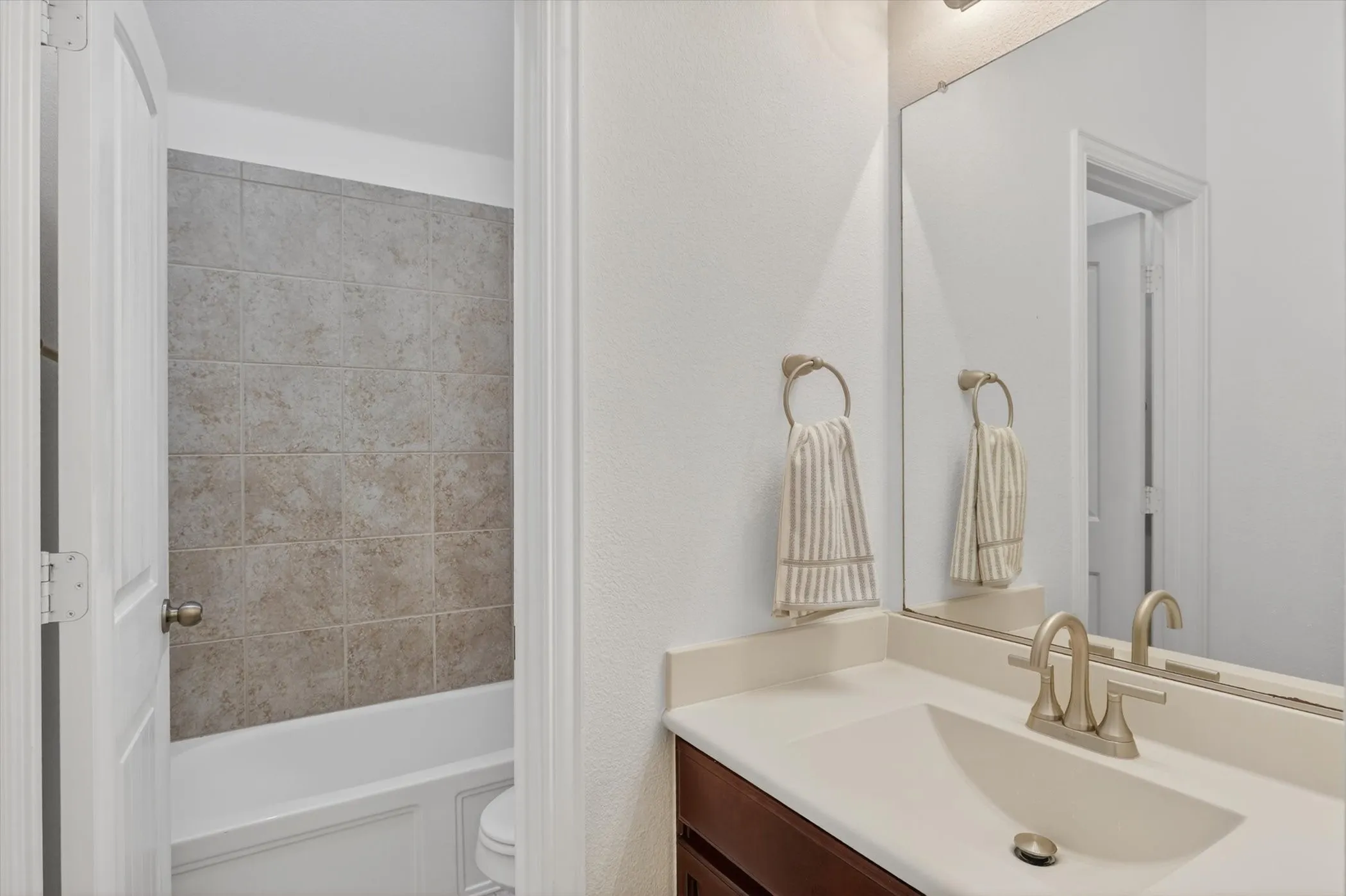Bathroom vanity featuring a light-toned countertop, integrated sink, and brushed nickel faucet