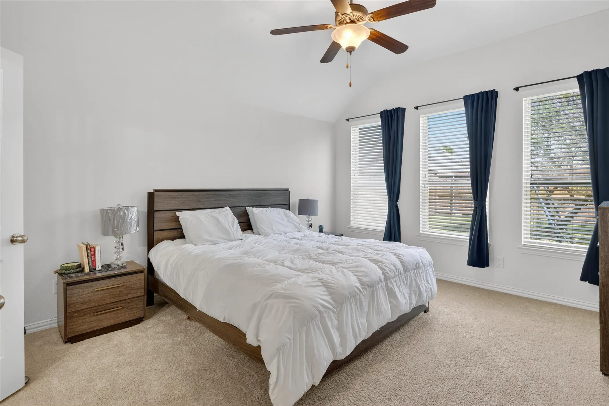 Carpeted room with a vaulted ceiling and a ceiling fan with integrated lighting