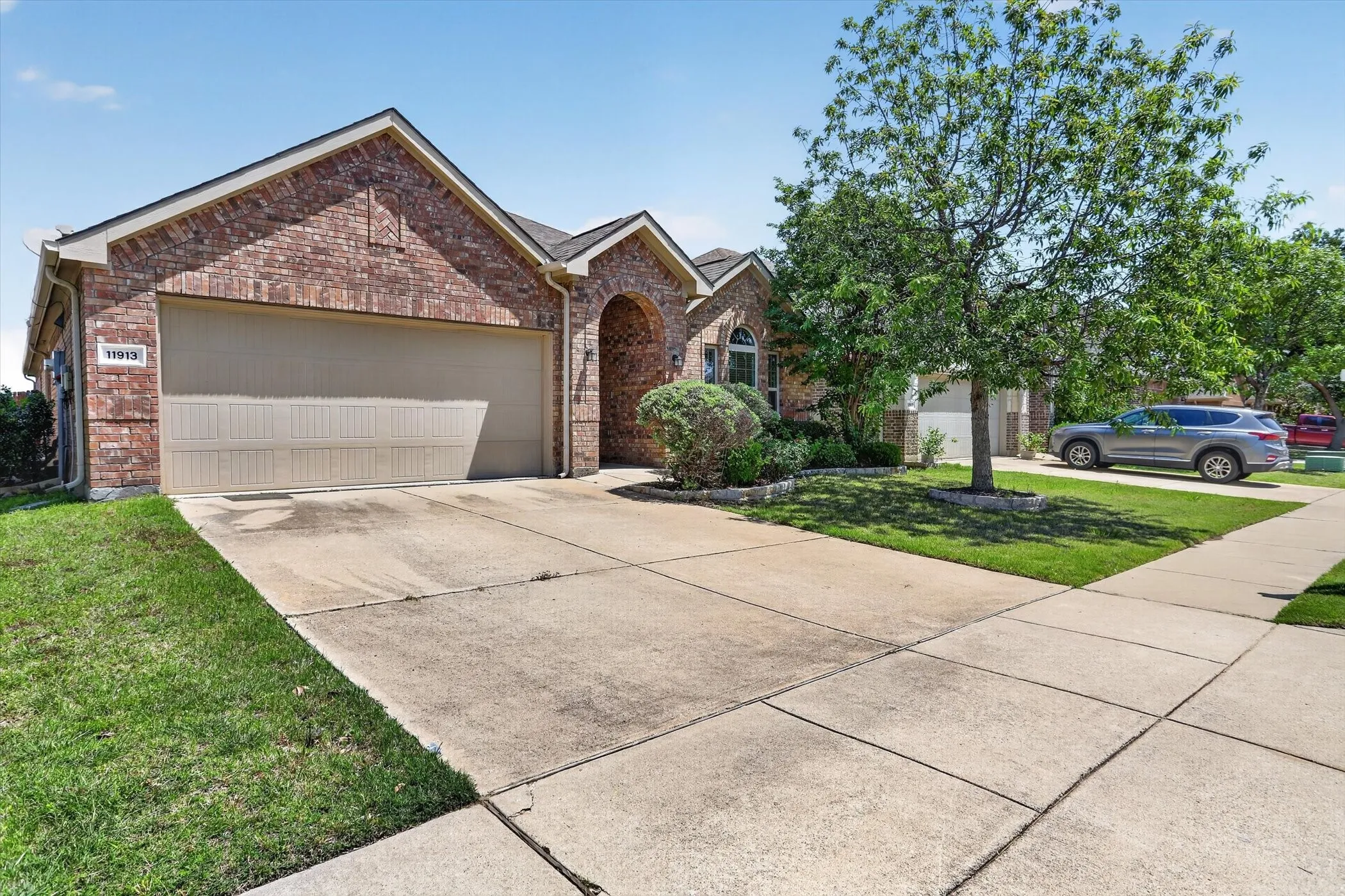 Brick facade with an arched entry, a two-car garage, and a concrete driveway