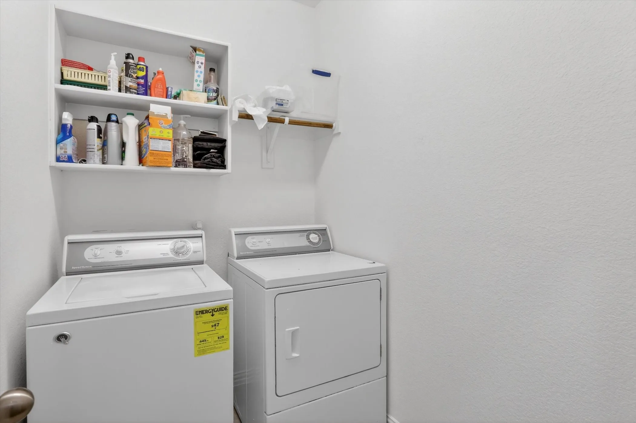 Dedicated laundry area featuring built-in shelving, a wall-mounted shelf, and space for a washer and dryer