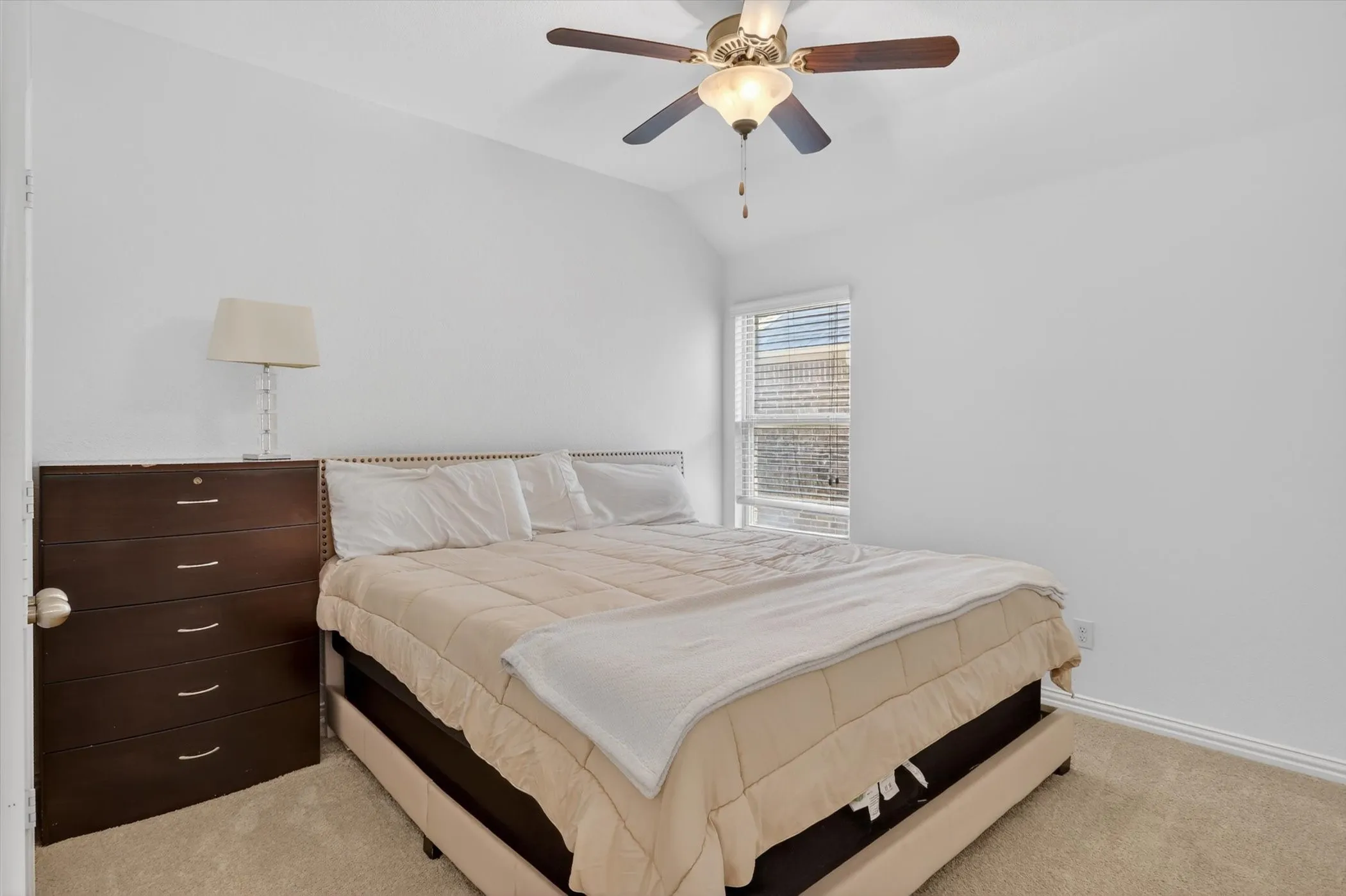Carpeted room featuring a ceiling fan with light fixture, a window with blinds, and white walls