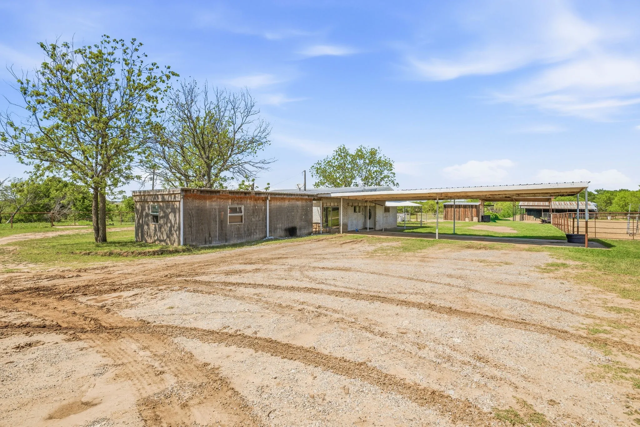 View of front of property featuring dirt driveway, an outbuilding, and a carport