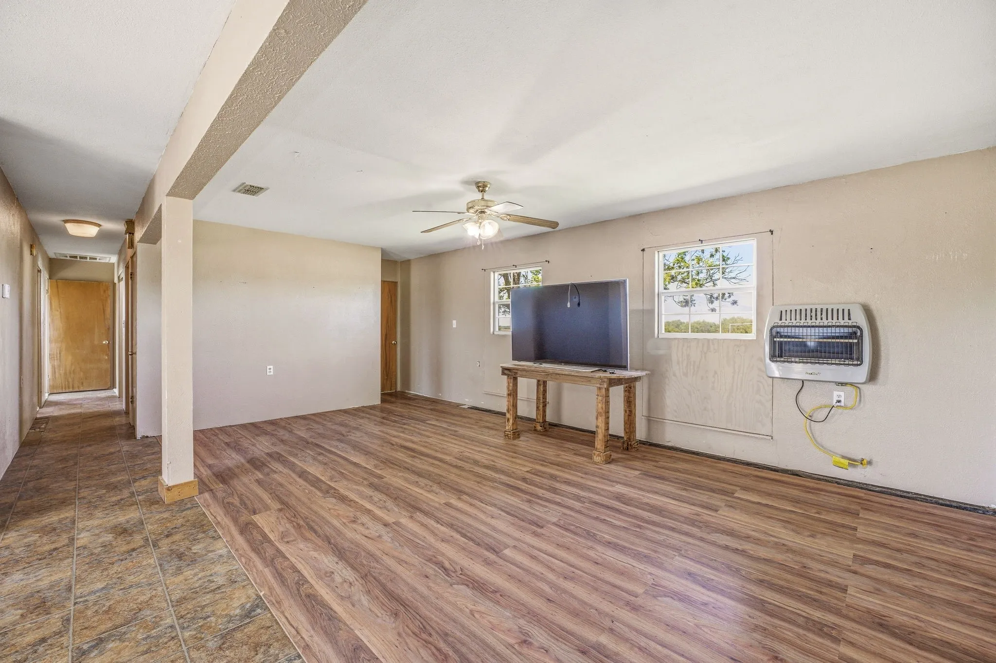 Unfurnished living room featuring wood finished floors, ceiling fan, and heating unit