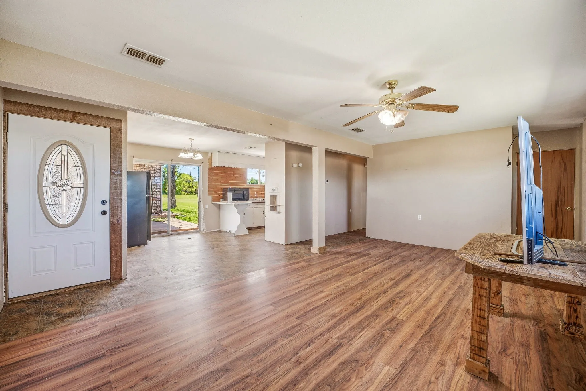 Unfurnished living room featuring wood finished floors, a ceiling fan, and hanging lights
