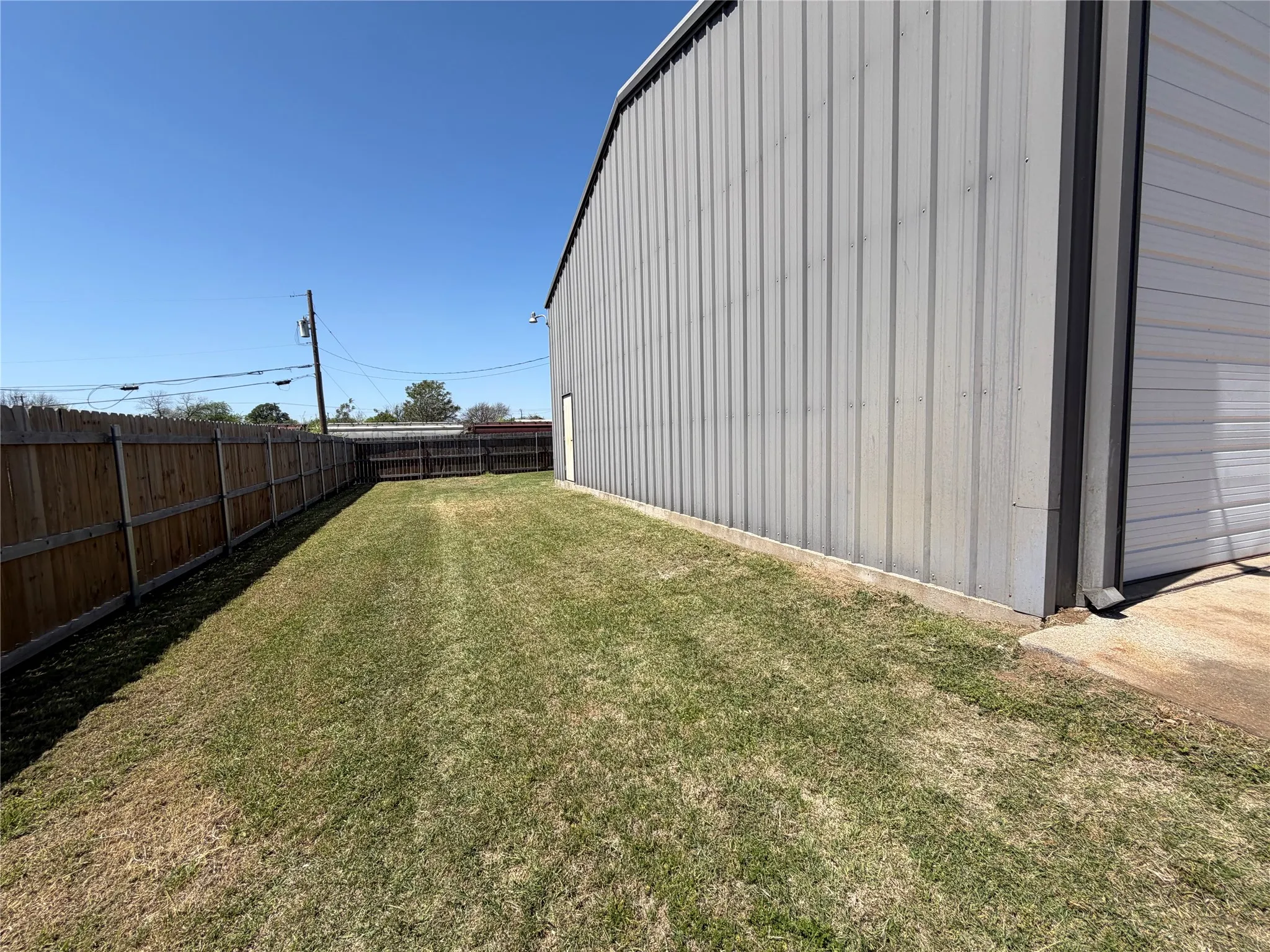 Fenced backyard with a garage and an outbuilding
