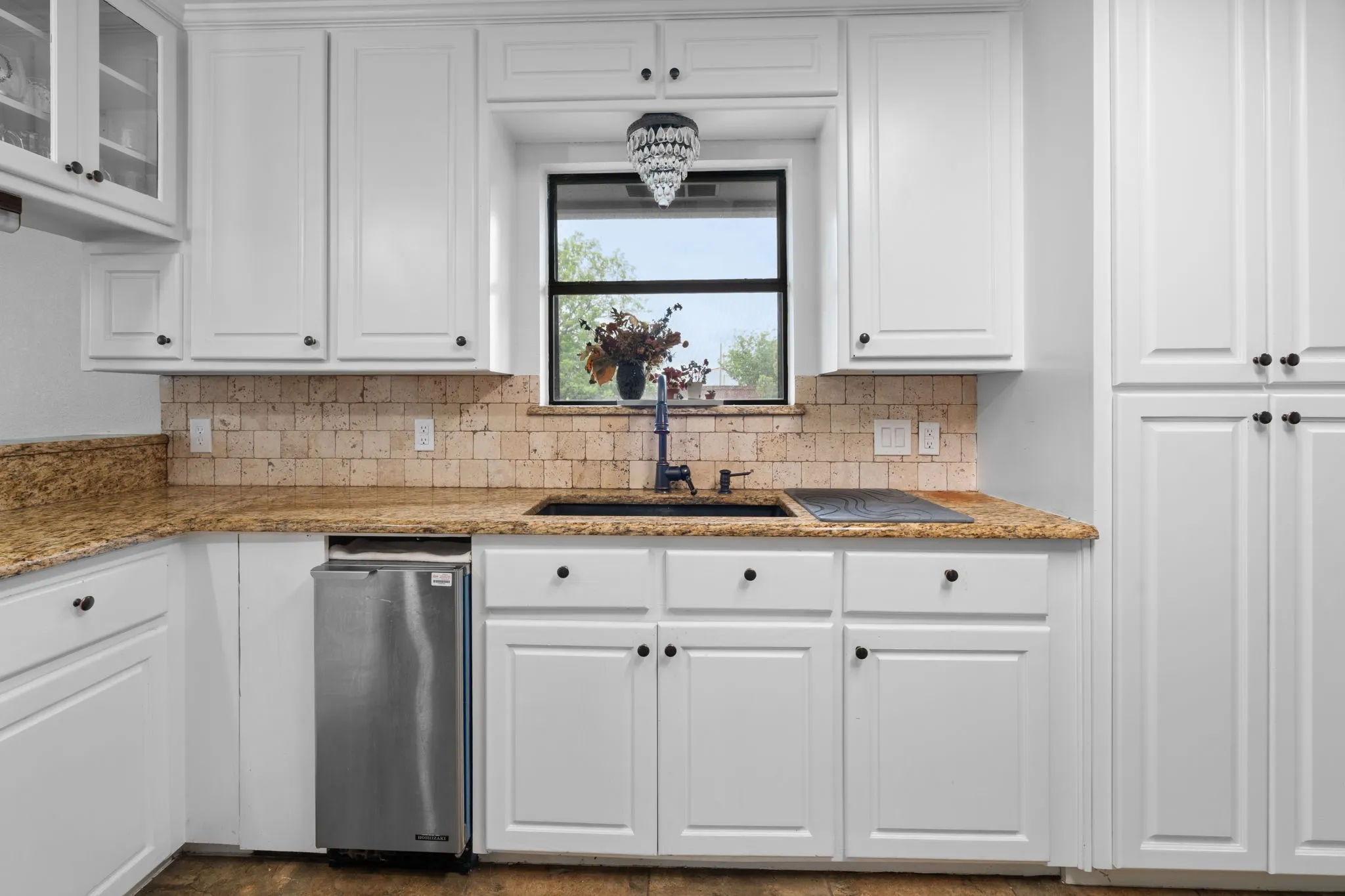 Kitchen featuring white cabinetry, light stone countertops, tasteful backsplash, and glass insert cabinets