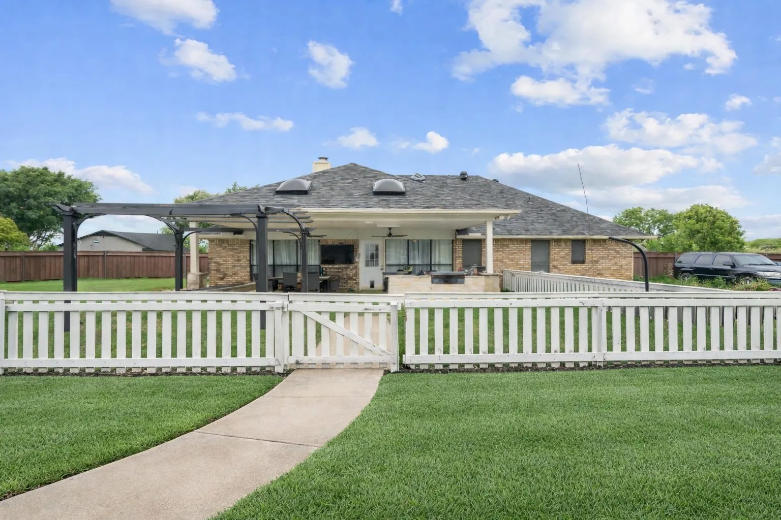 View of front of property featuring a gate, a chimney, a fenced front yard, a patio area, and brick siding