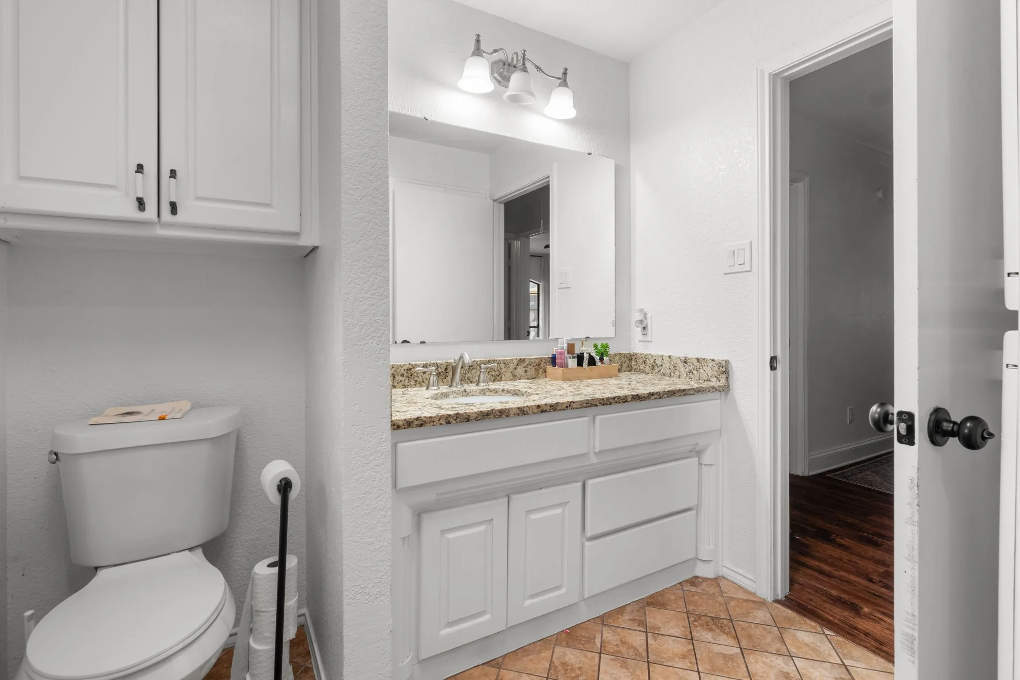 Half bathroom featuring vanity, a textured wall, and light tile patterned floors