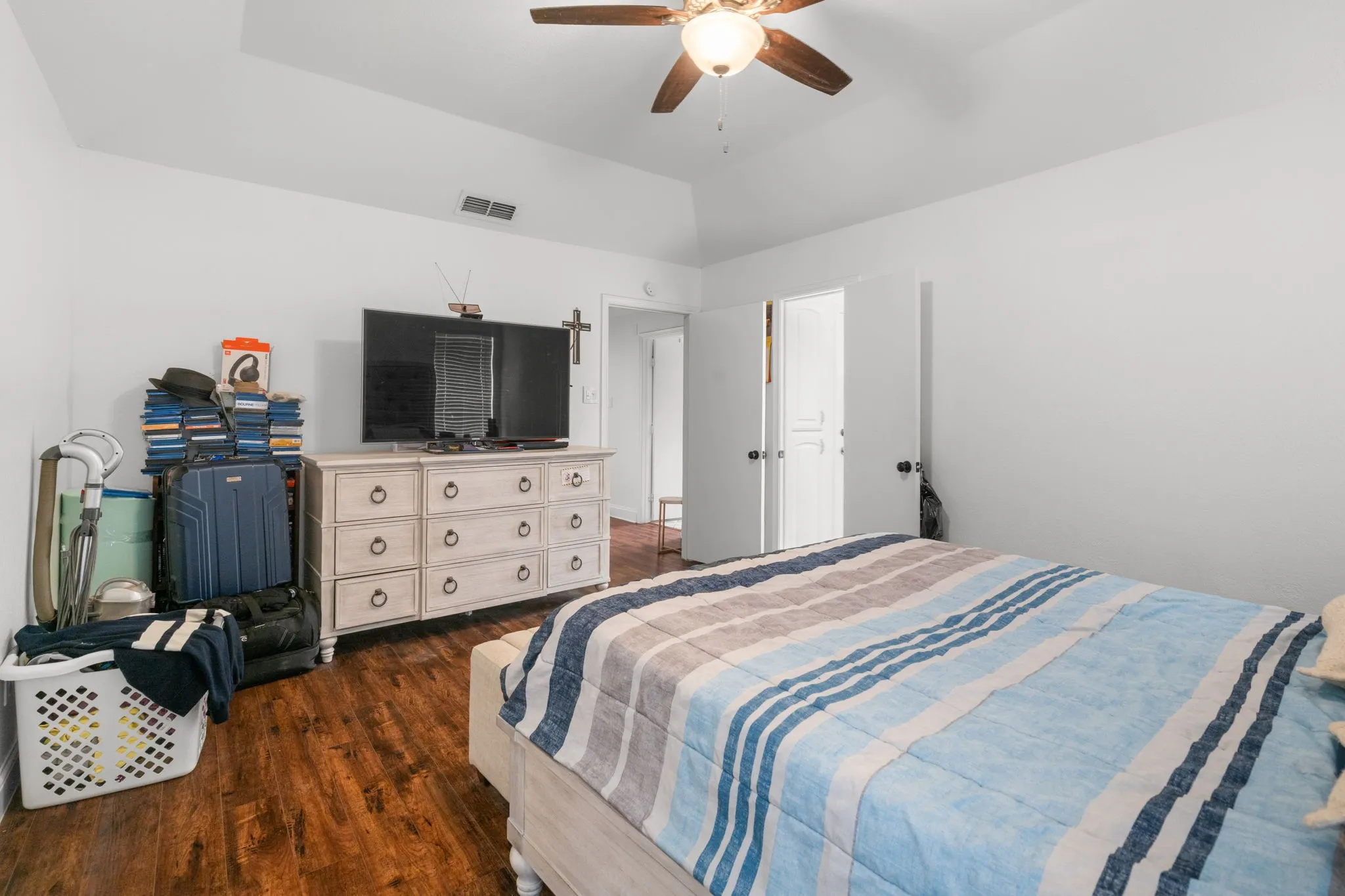 Bedroom with dark wood-style floors, ceiling fan, and vaulted ceiling