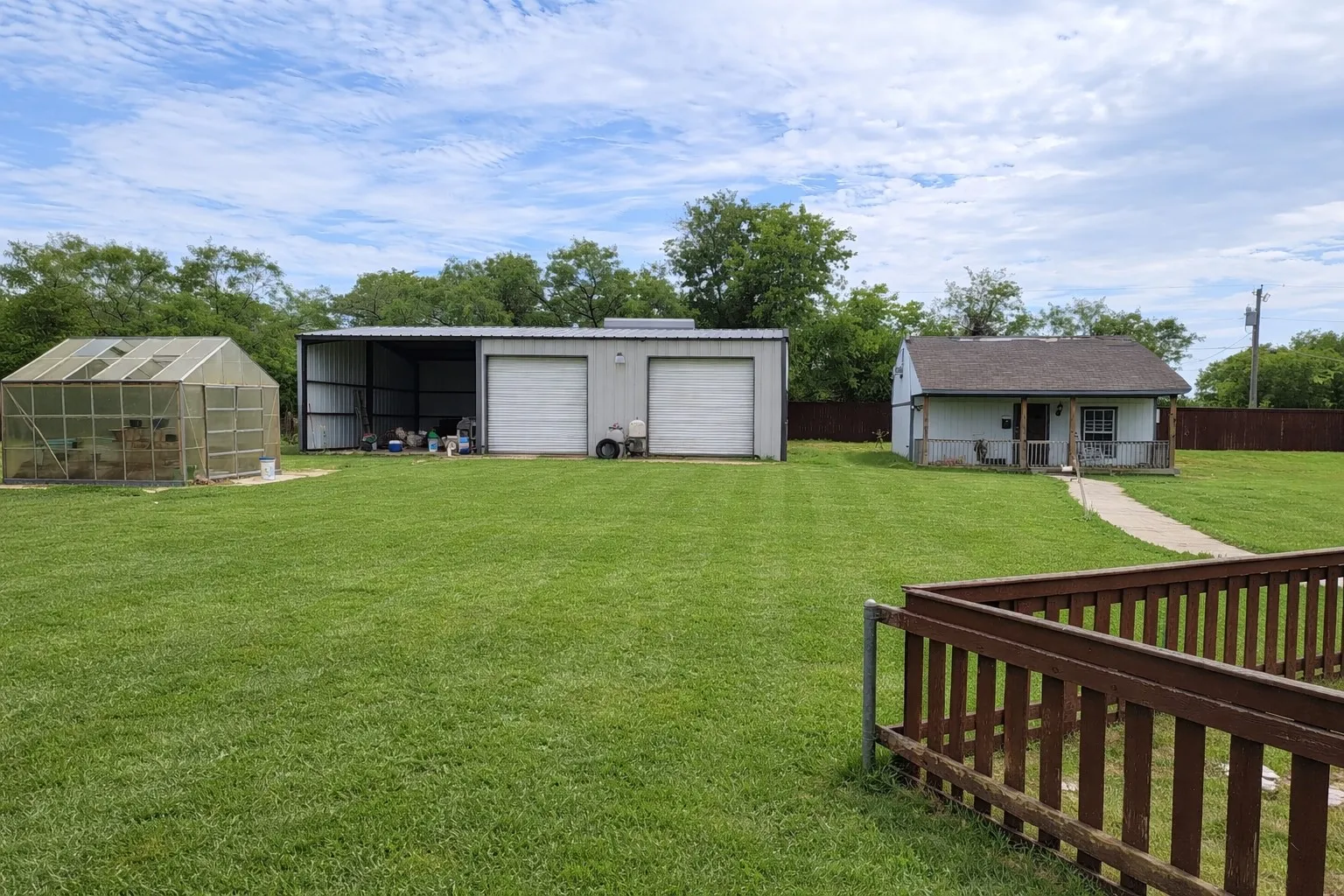 View of yard with an outdoor structure, a garage, and a greenhouse