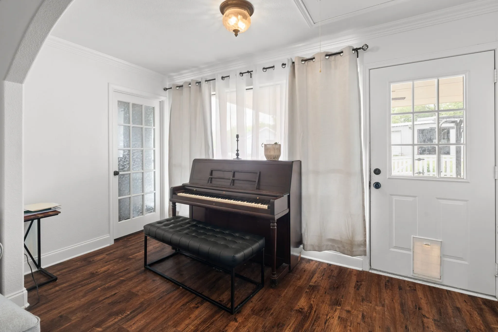 Living area featuring crown molding, dark wood-style floors, and arched walkways