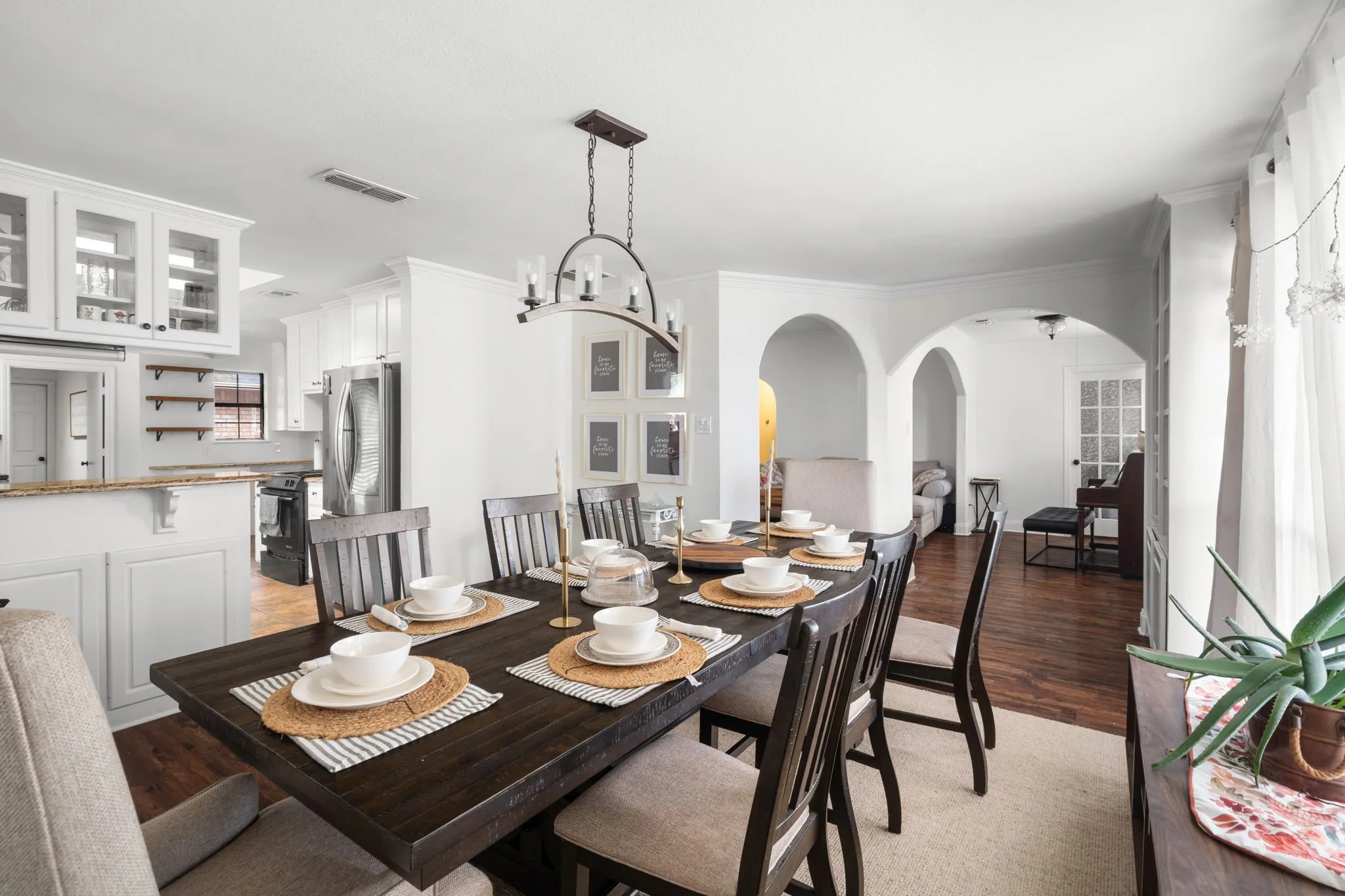 Dining room featuring arched walkways, light wood-style flooring, and hanging lights