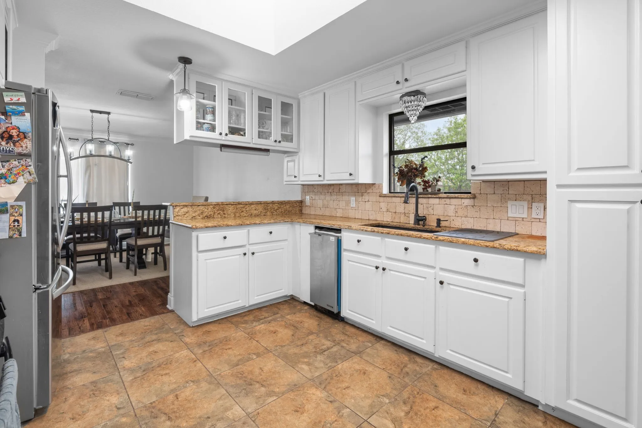 Kitchen featuring glass insert cabinets, light stone counters, white cabinetry, and stainless steel appliances