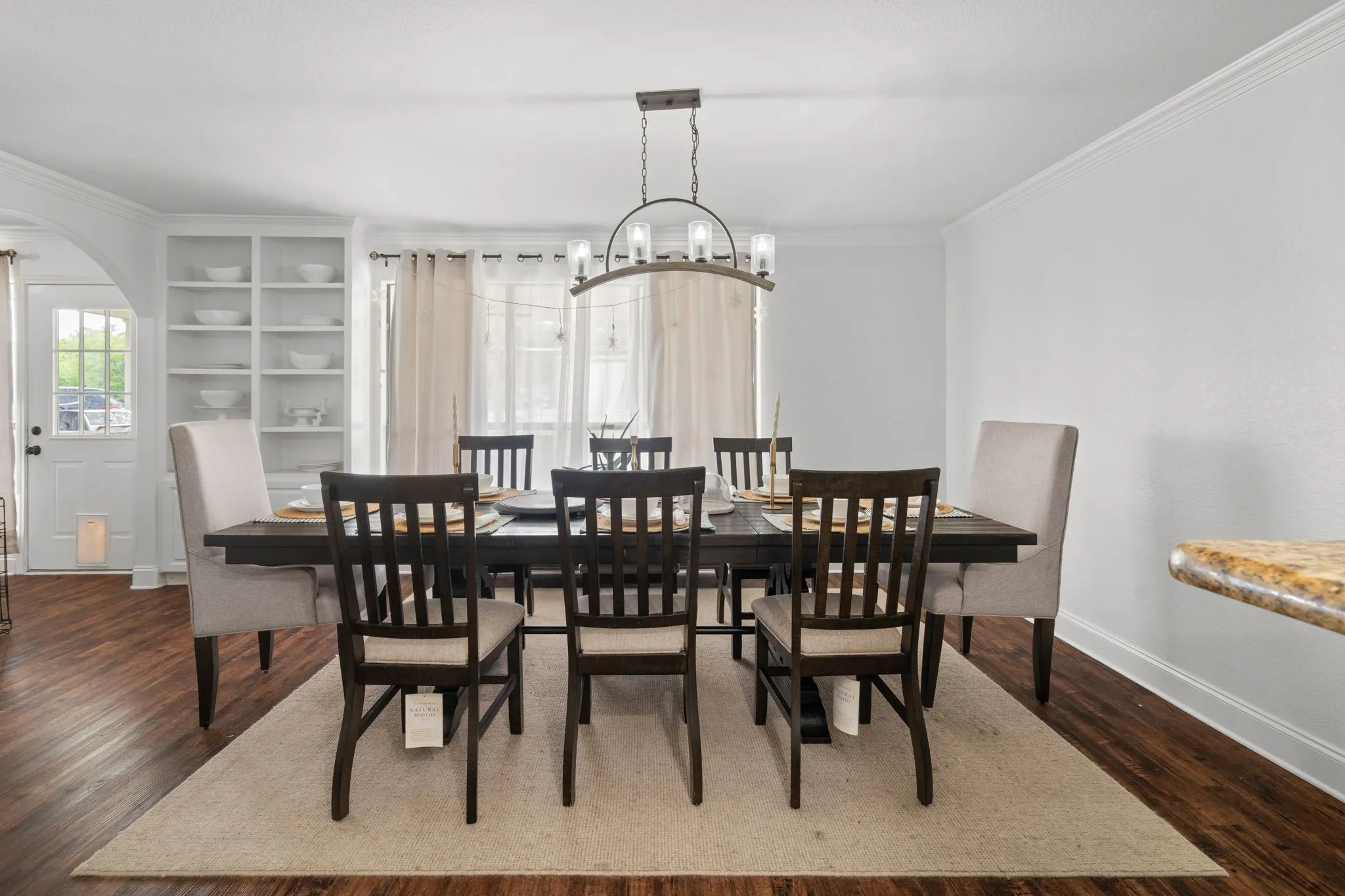 Dining space featuring ornamental molding, arched walkways, dark wood-type flooring, and suspended lighting