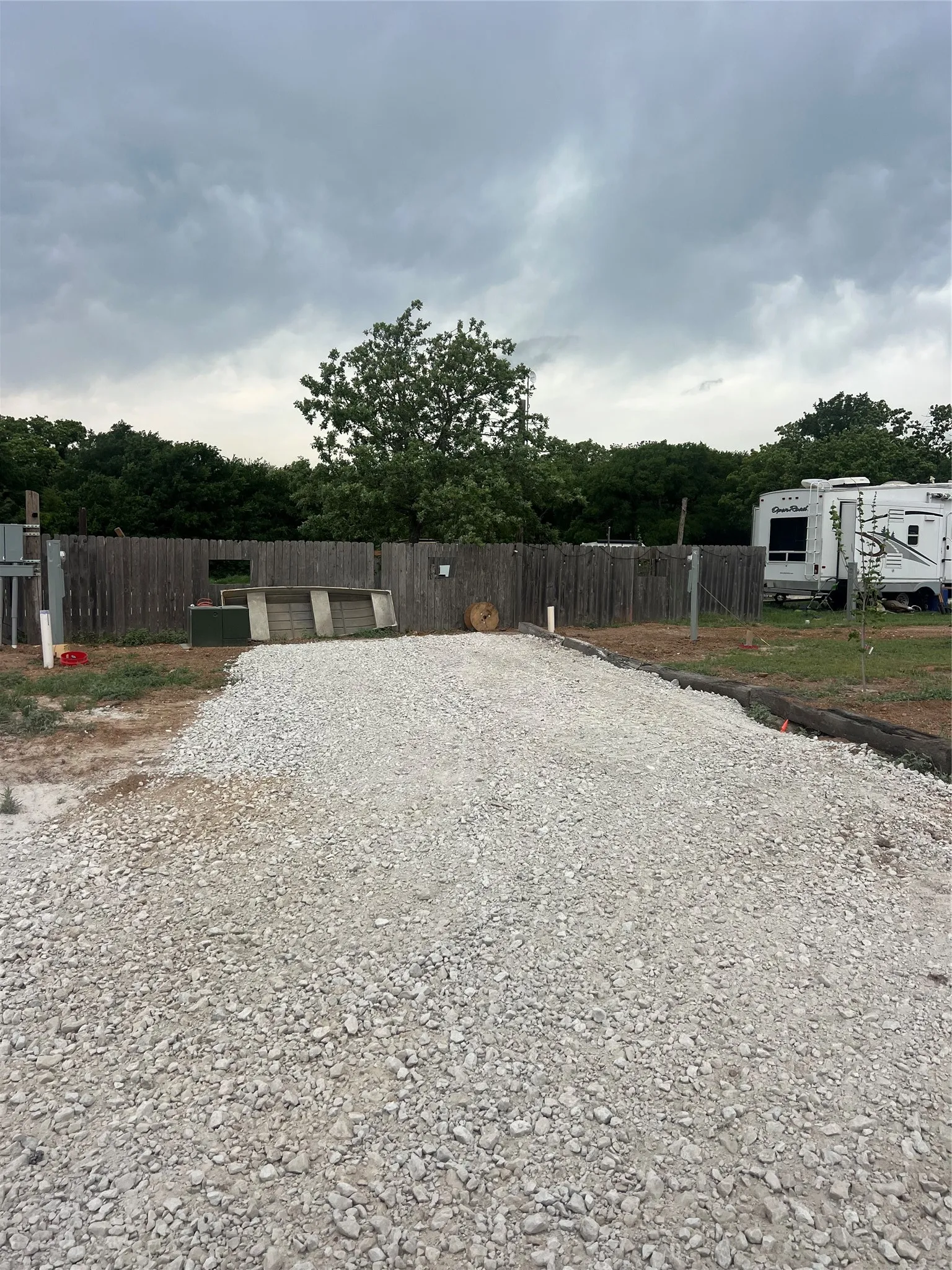 The property features a gravel ground surface and a wooden fence along the perimeter