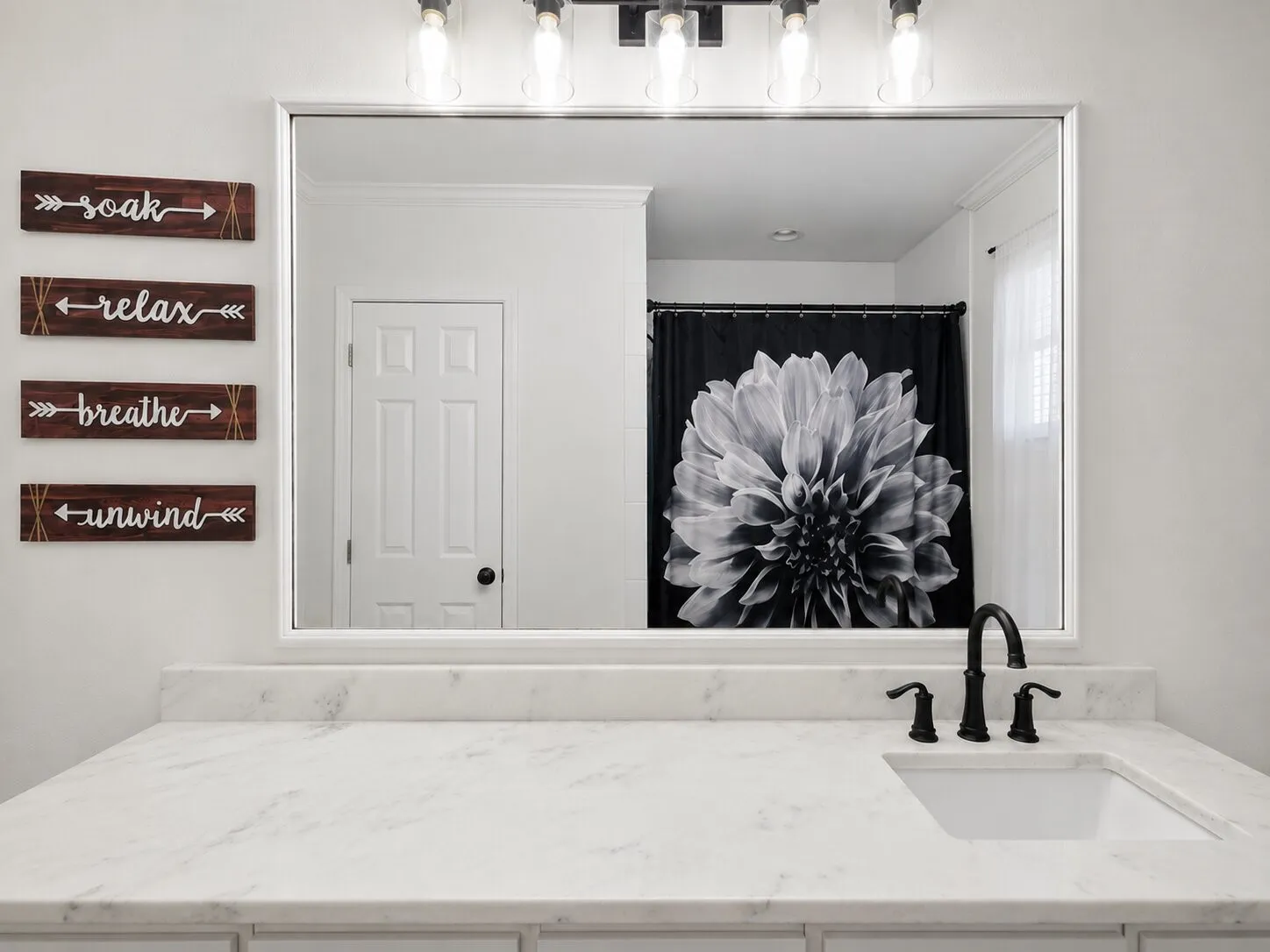 White vanity with a single undermount sink, a matte black faucet, and a light-toned countertop