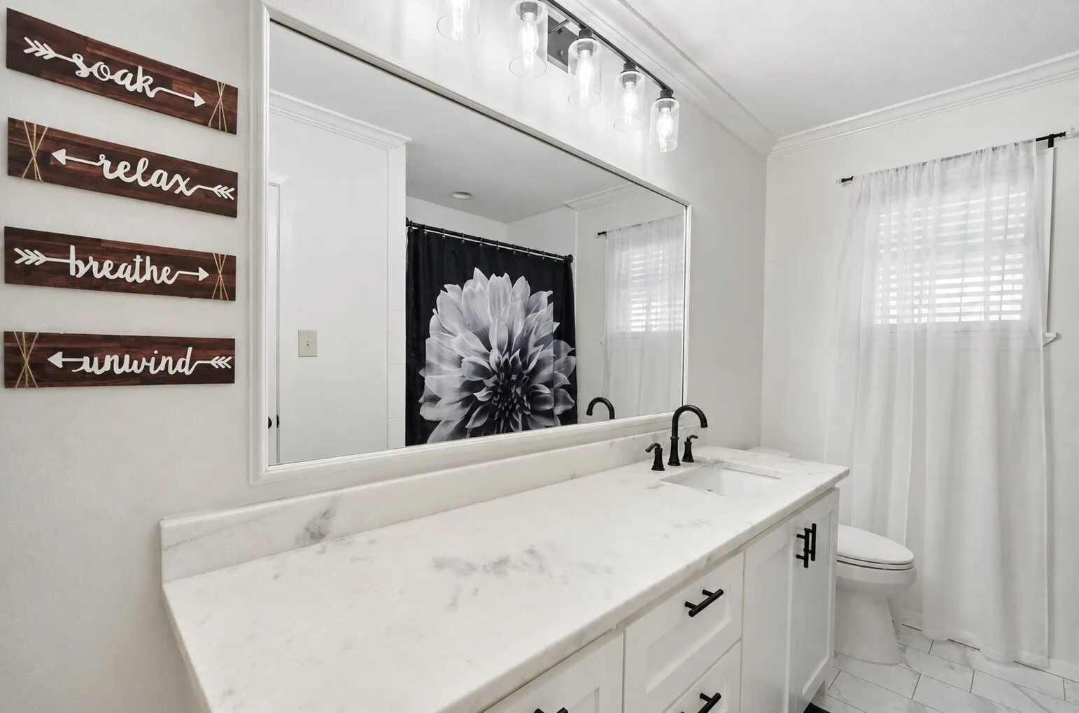 Bathroom vanity featuring a light-toned countertop with an integrated sink and matte black hardware